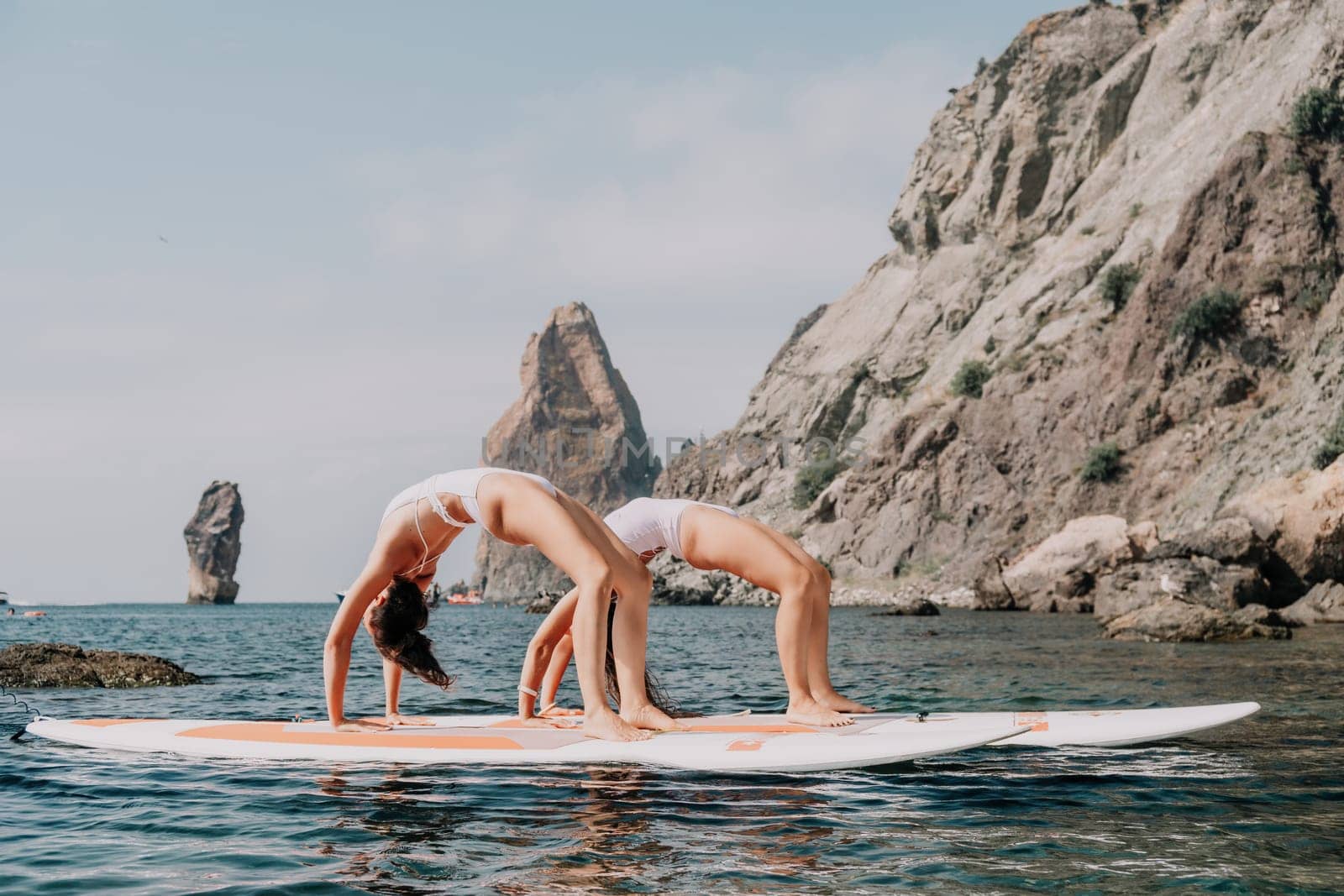 Woman sup yoga. Happy sporty woman practising yoga pilates on paddle sup surfboard. Female stretching doing workout on sea water. Modern individual female hipster outdoor summer sport activity. by panophotograph