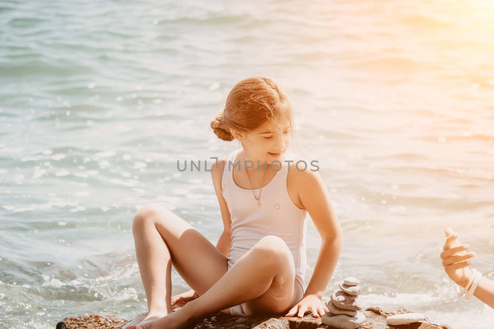 Balanced Pebbles Pyramid on the Beach on Sunny Day and Clear Sky at Sunset. Blue Sea on Background Selective focus, zen stones on sea beach, meditation, spa, harmony, calm, balance concept.