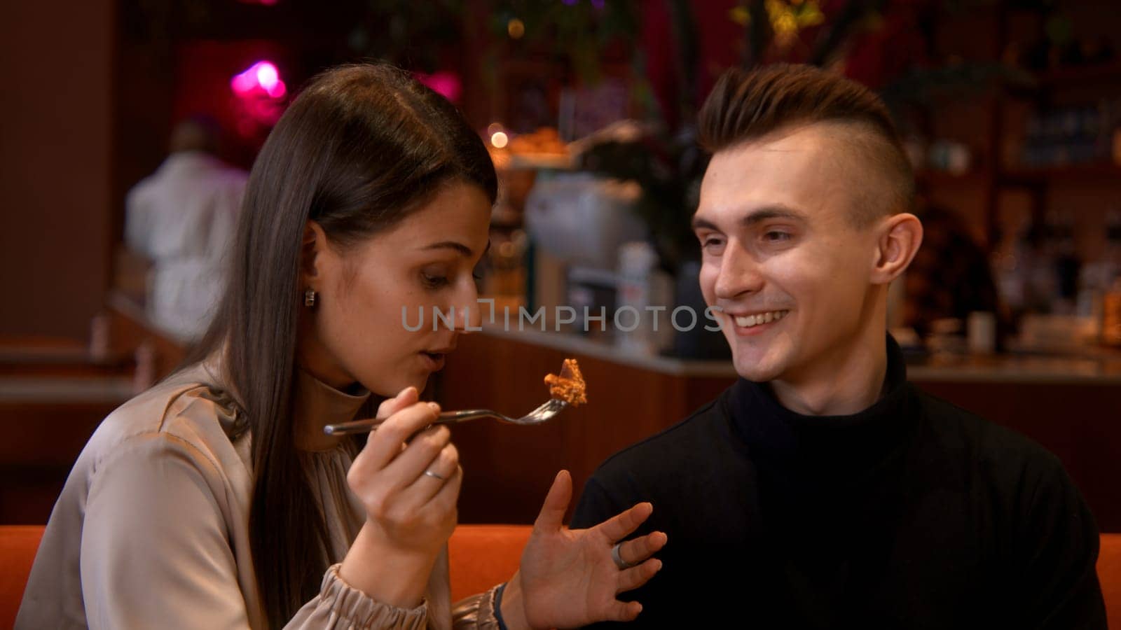 Young couple sitting in modern cafe on date. Stock footage. Caucasian girl and guy talk to each other on romantic date