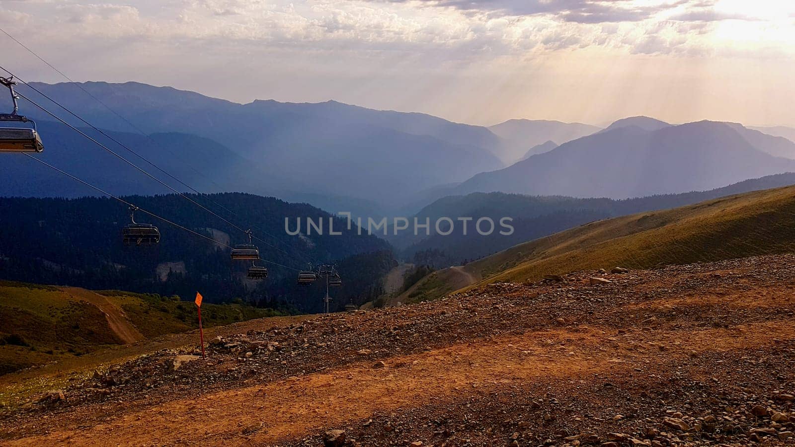 A view of a valley with mountains in the background. The sun shines on the mountains in the distance, featured on unsplash, superflat, panorama, creative commons attribution