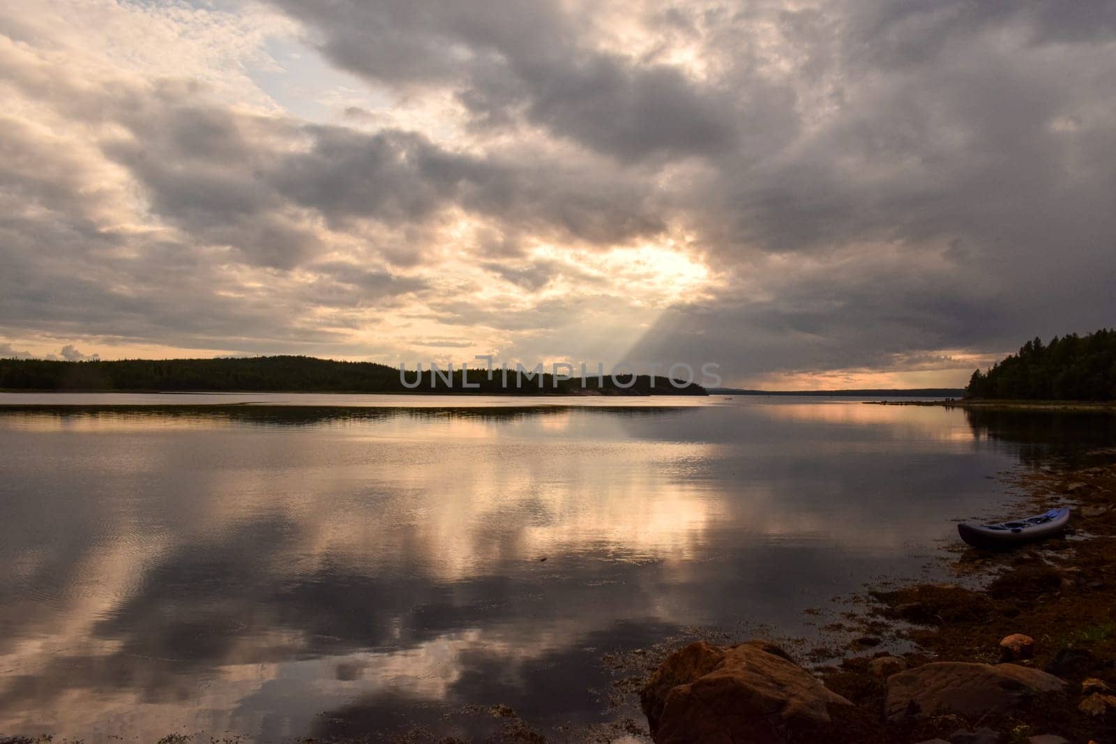 A boat sitting on the shore of a lake under a cloudy sky, flickering light, photo taken with ektachrome, anamorphic lens flare