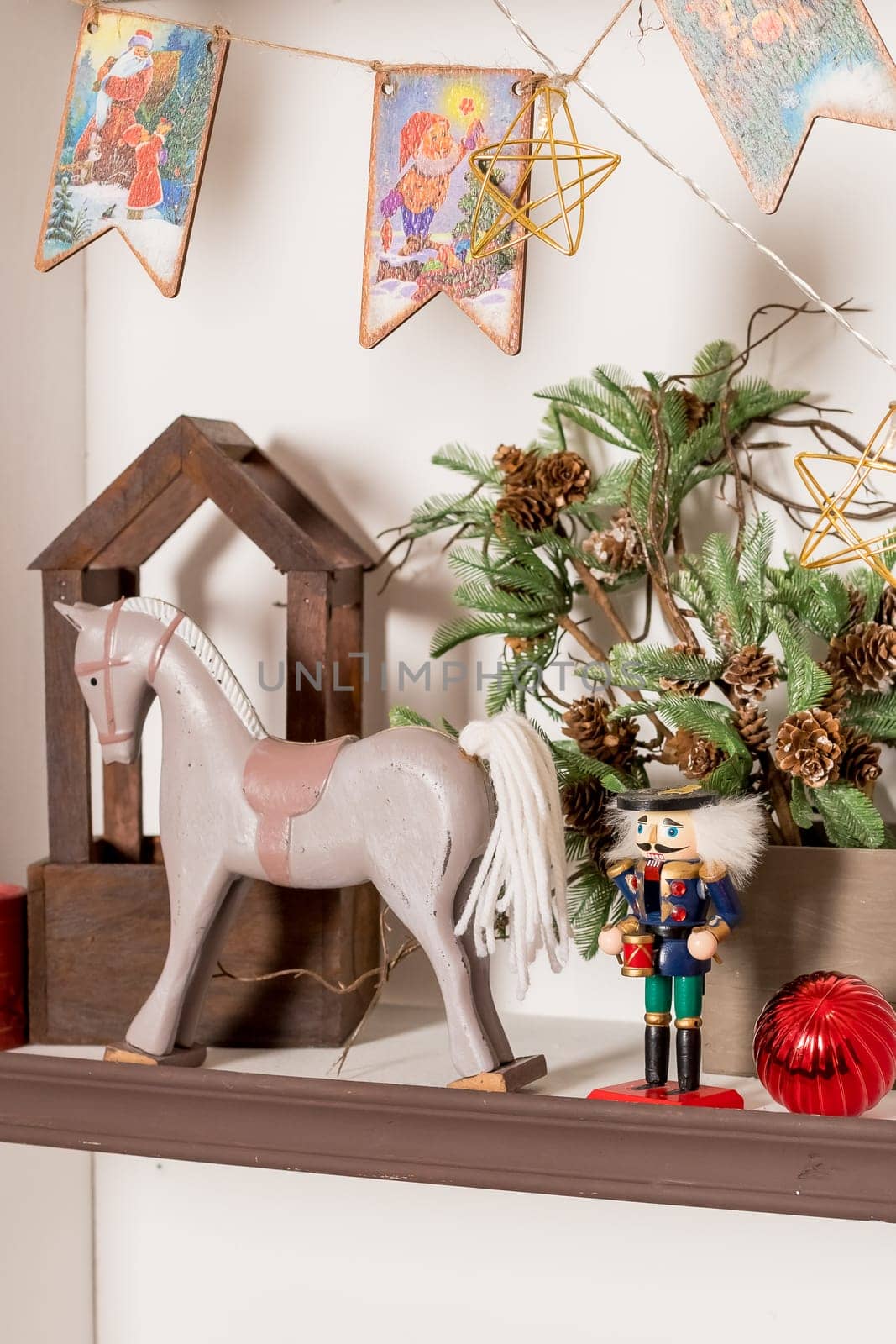 wooden interior decorations in the form of houses with a Nutcracker figurine and an elegant deer on the background of Christmas tree branches in a shopping center