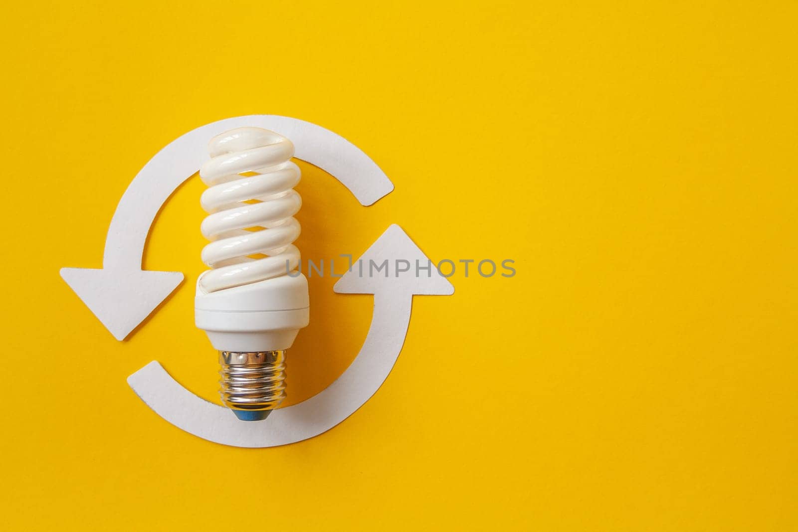 Energy saving light bulb and recycle arrows. Economical consumption of electricity. Orange background . The concept of nature conservation and renewable energy sources with place for text
