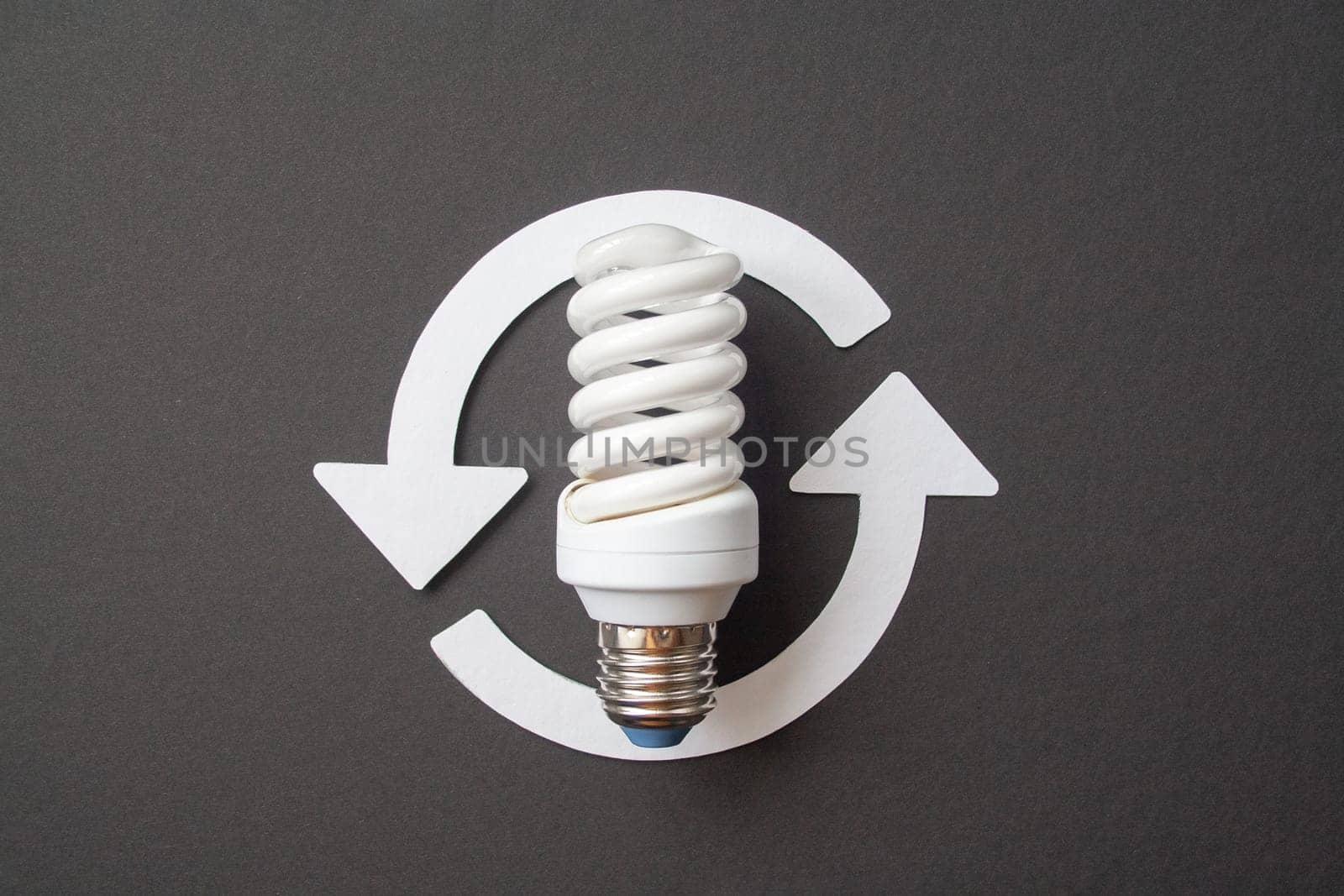Energy saving light bulb on a black background by Quils