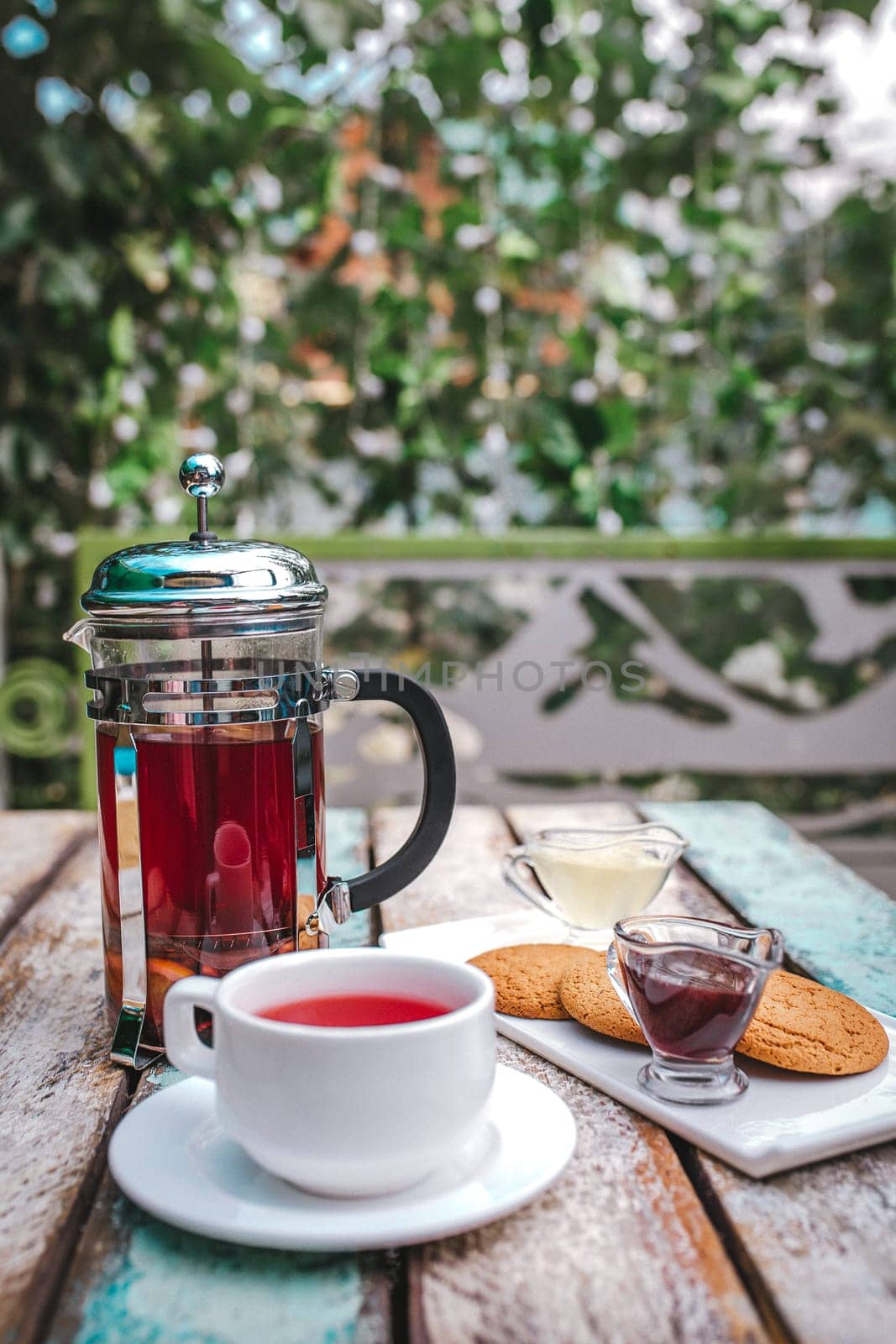 glass teapot tea and cookies on a wooden table outside by Pukhovskiy