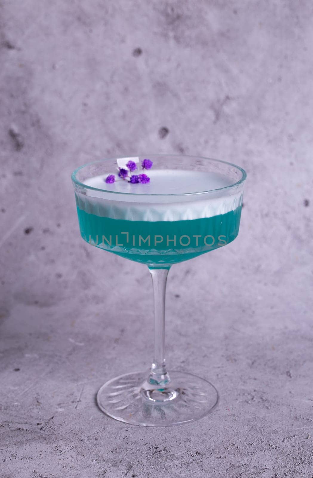 turquoise cocktail with a flower on a gray background by Pukhovskiy