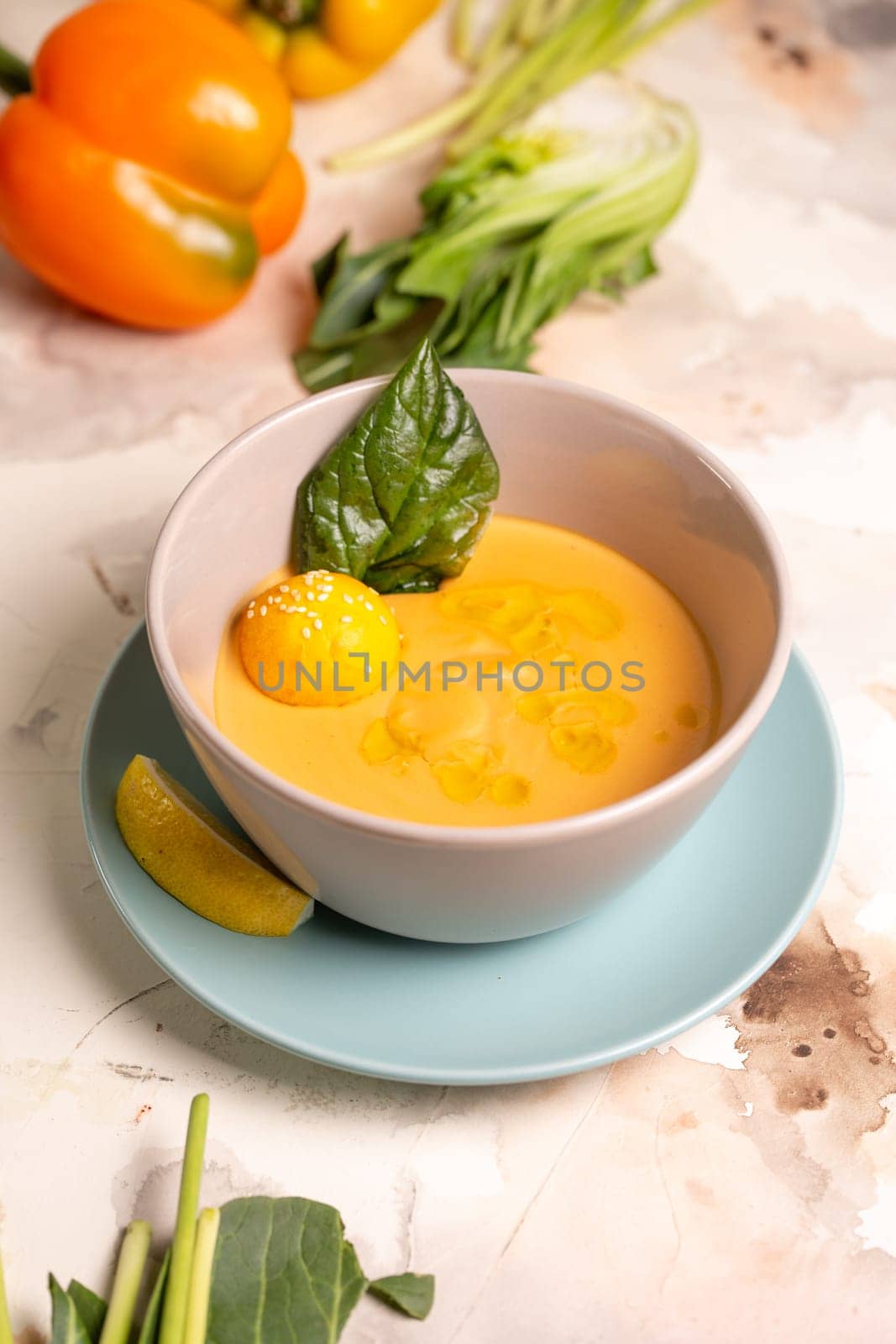 pumpkin cream soup with a slice of lemon in a plate on the table.