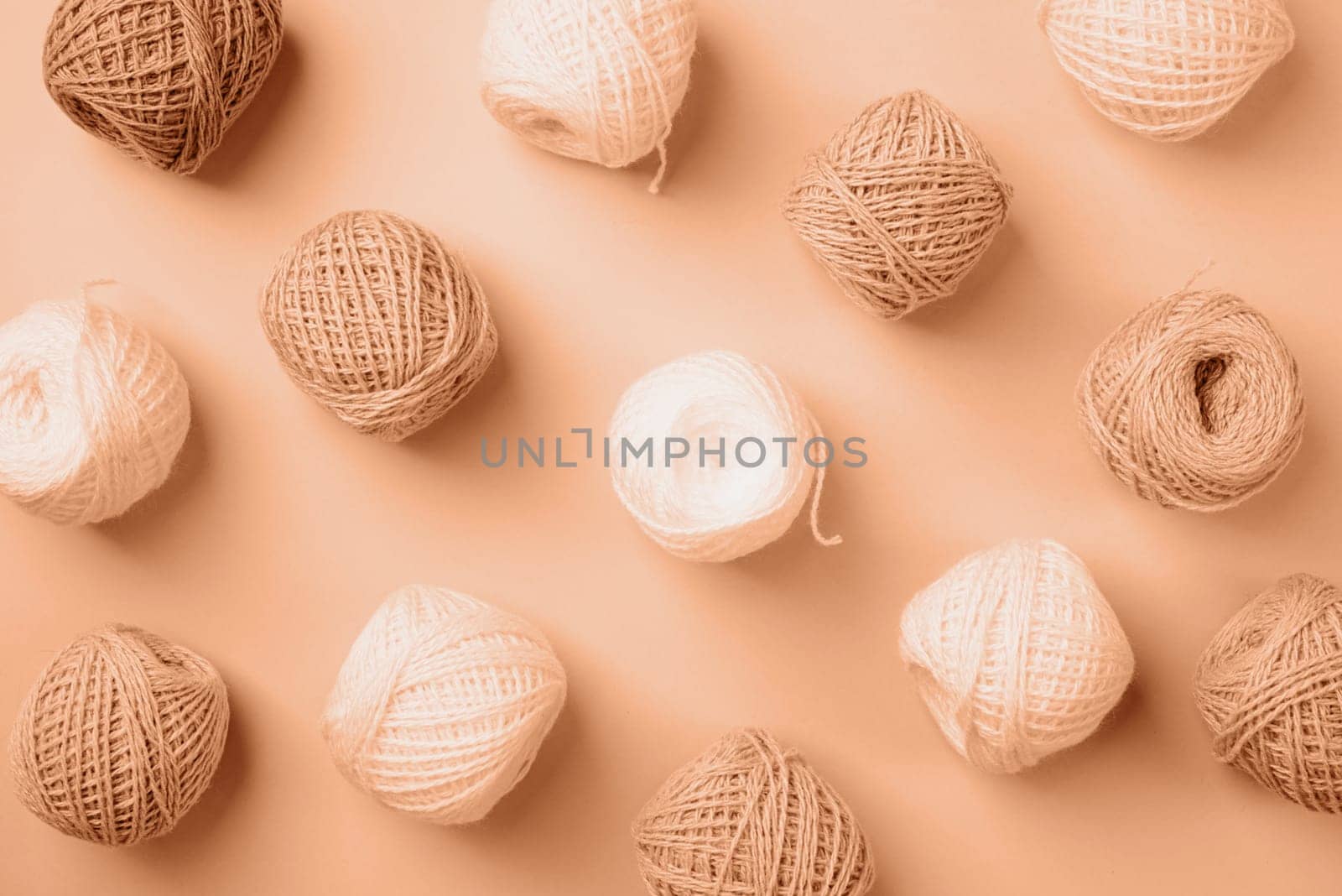 Color of the year 2024: Peach Fuzz. pastel and beige colored yarn wool on beige backdrop, top view flat lay. Knitting pattern