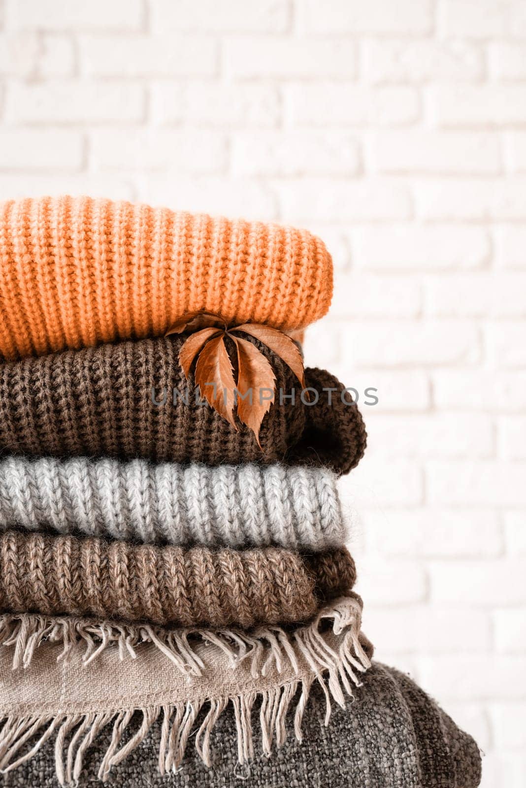 Color of the year 2024: Peach Fuzz. Hello fall. Cozy warm image. Stack of colorful autumn warm sweaters