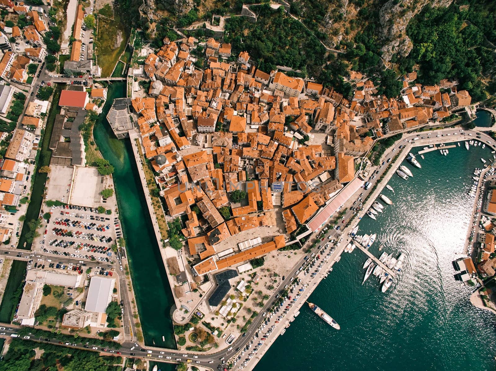 Pier with moored boats off the coast of the town of Kotor with the red roofs of ancient buildings. Montenegro. Drone. High quality photo