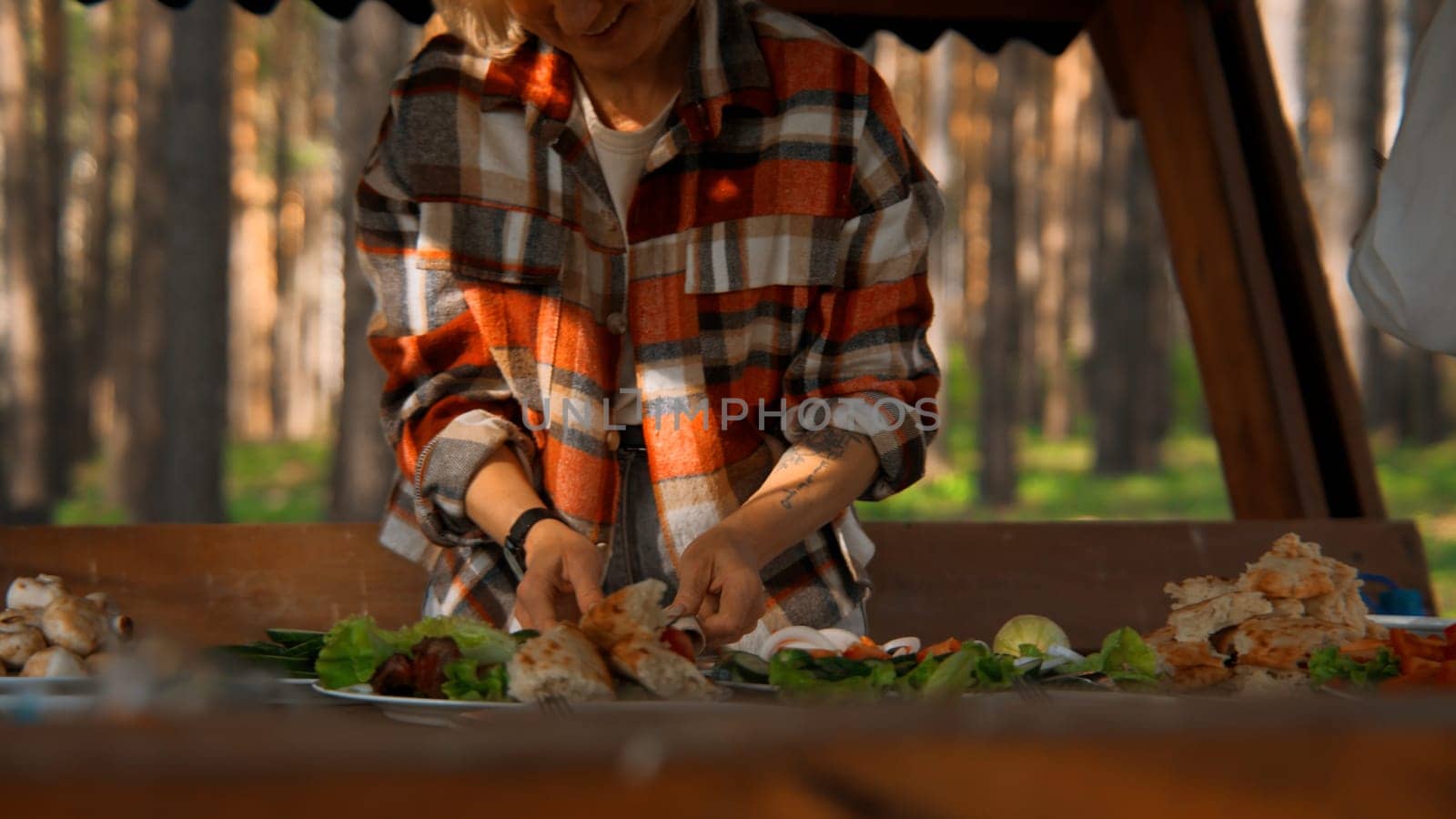 Woman serving table at outdoors picnic. Stock footage. Summer forest and bbq