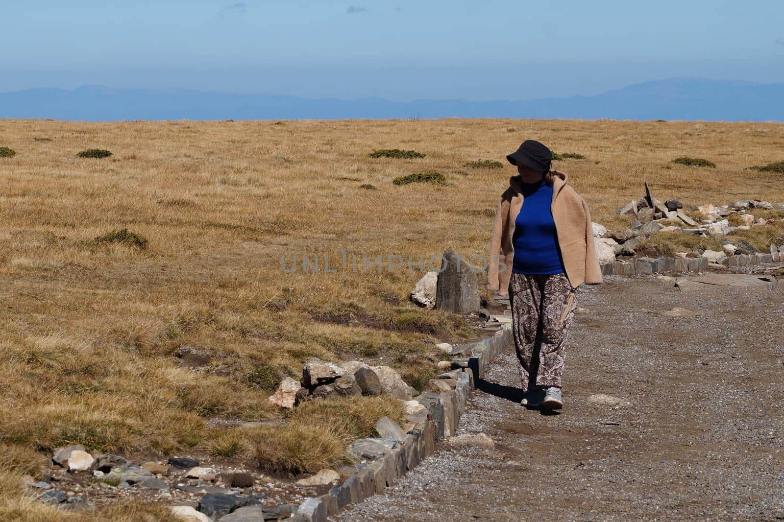 An elderly woman travels through a mountainous area.