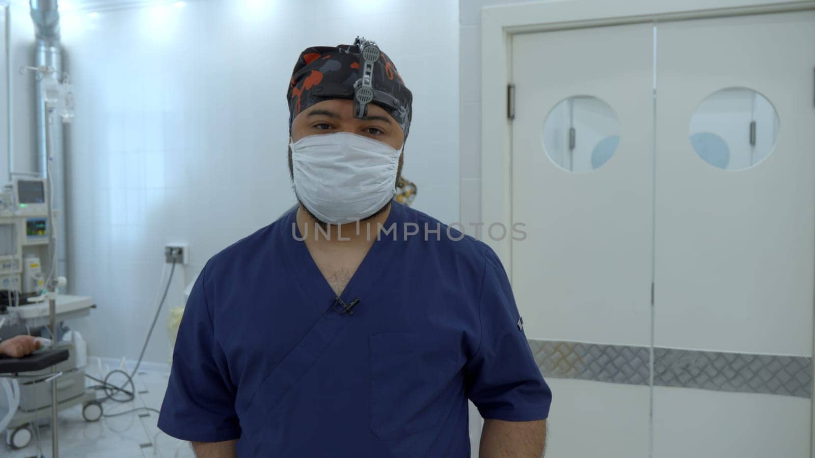 Medical doctor with a binocular magnifier in a mask. Action. Background of an operating theatre