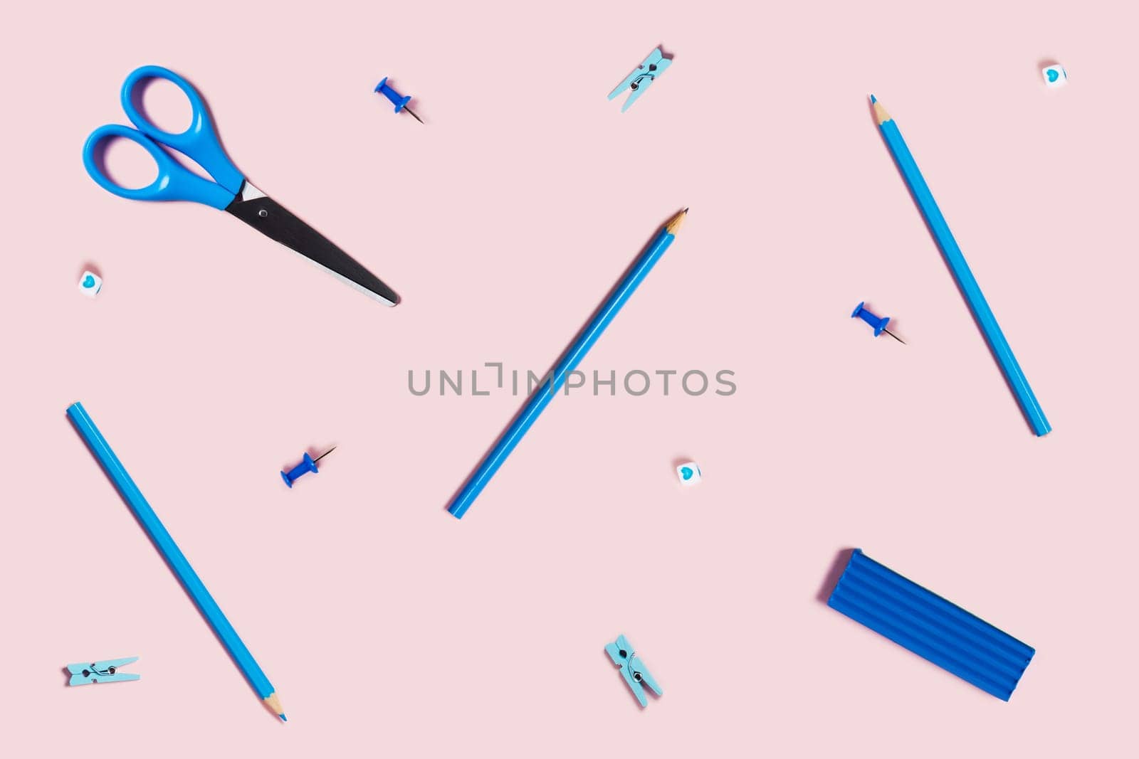 Photography on the theme of home education. Children's pink desktop with scattered blue writing accessories.