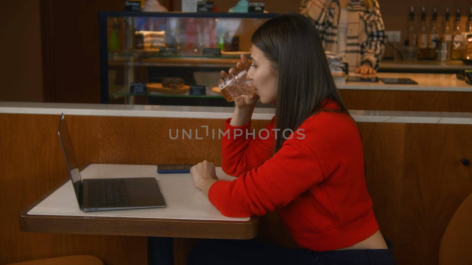 Beautiful woman is seriously working at laptop in cafe. Stock footage. Attractive young woman is working thoughtfully at laptop. Woman works with clients on freelance basis from laptop in cafe.
