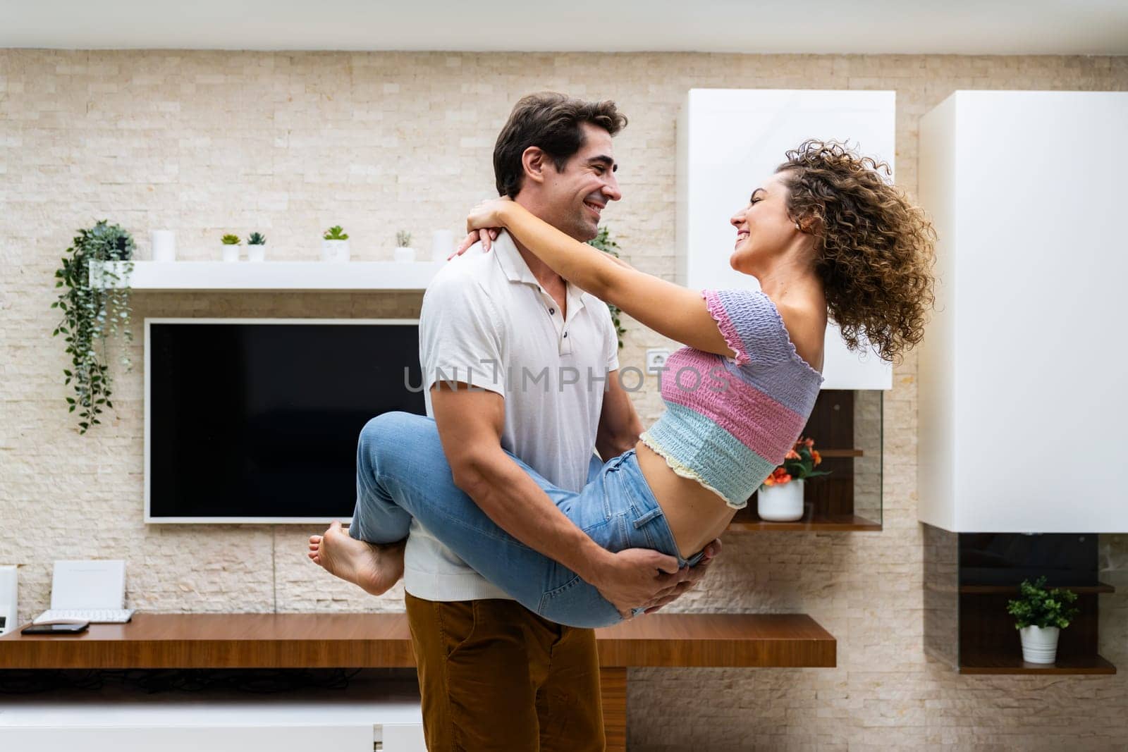 Smiling couple embracing in modern living room near TV by javiindy
