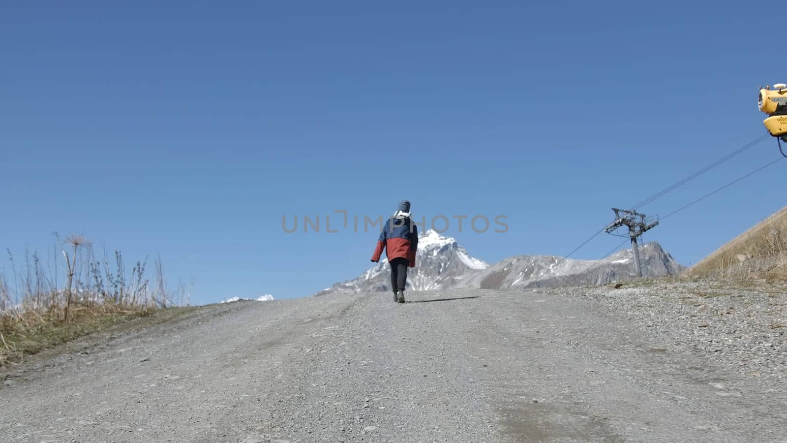 Boy goes up mountain road. Creative. Boy is walking on road uphill. Boy climbs mountains on road on autumn sunny day.