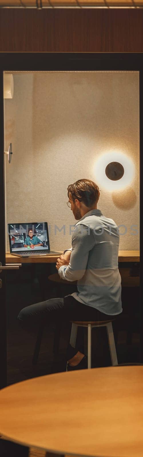 Male freelancer have a videoconference with colleague while sitting in cozy coworking by Yaroslav_astakhov