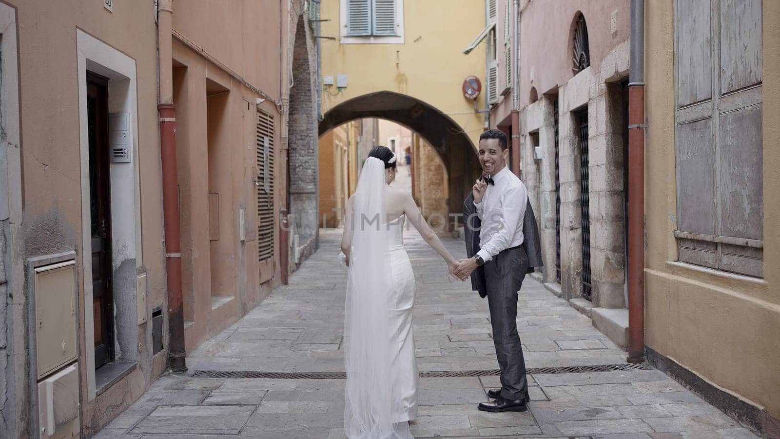 Newlyweds walking around the city with bright houses. Action. A young couple walking hand in hand along narrow roads between houses. High quality 4k footage