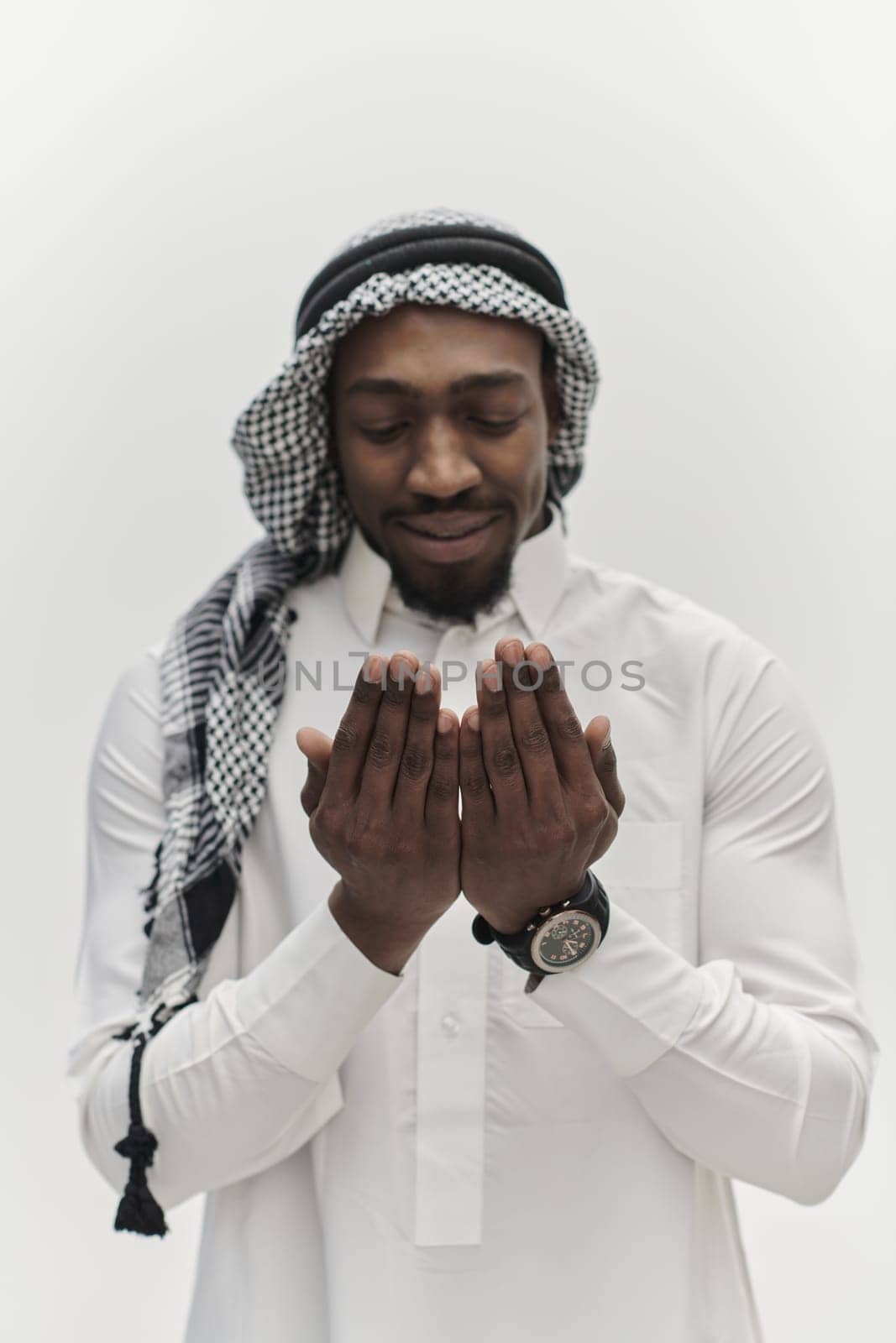 African American Muslim man raises his hands in prayer, seeking solace and devotion to God, as he stands isolated against a serene white backdrop, symbolizing a profound expression of faith and contemplation by dotshock