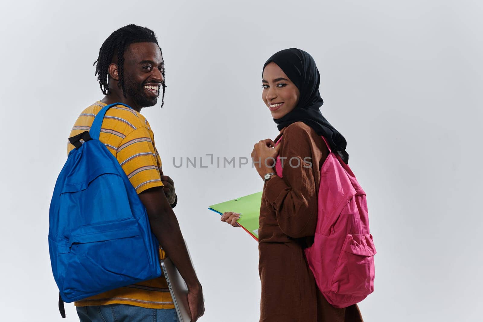 African American student collaborates with his Muslim colleague, who diligently works on her laptop, symbolizing a blend of diversity, modern learning, and cooperative spirit against a serene white background by dotshock
