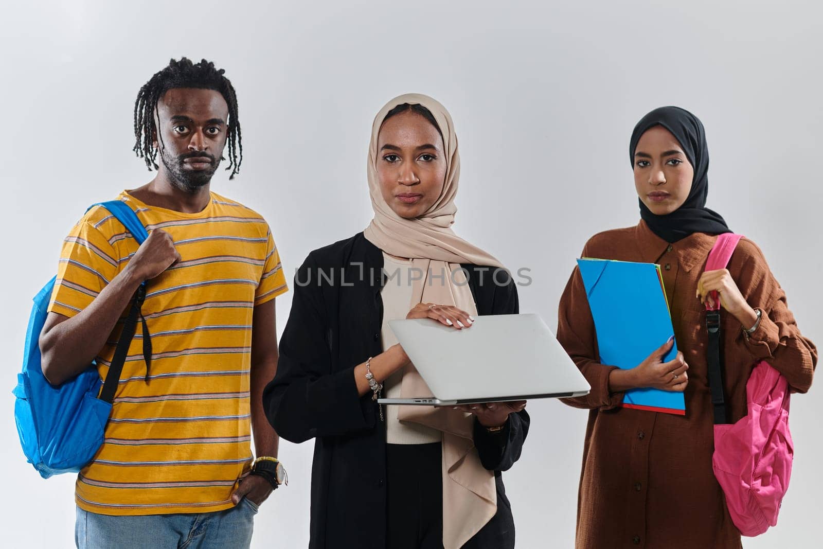 A group of students, including an African American student and two hijab-wearing women, stand united against a pristine white background, symbolizing a harmonious blend of cultures and backgrounds in the pursuit of knowledge and academic excellence by dotshock