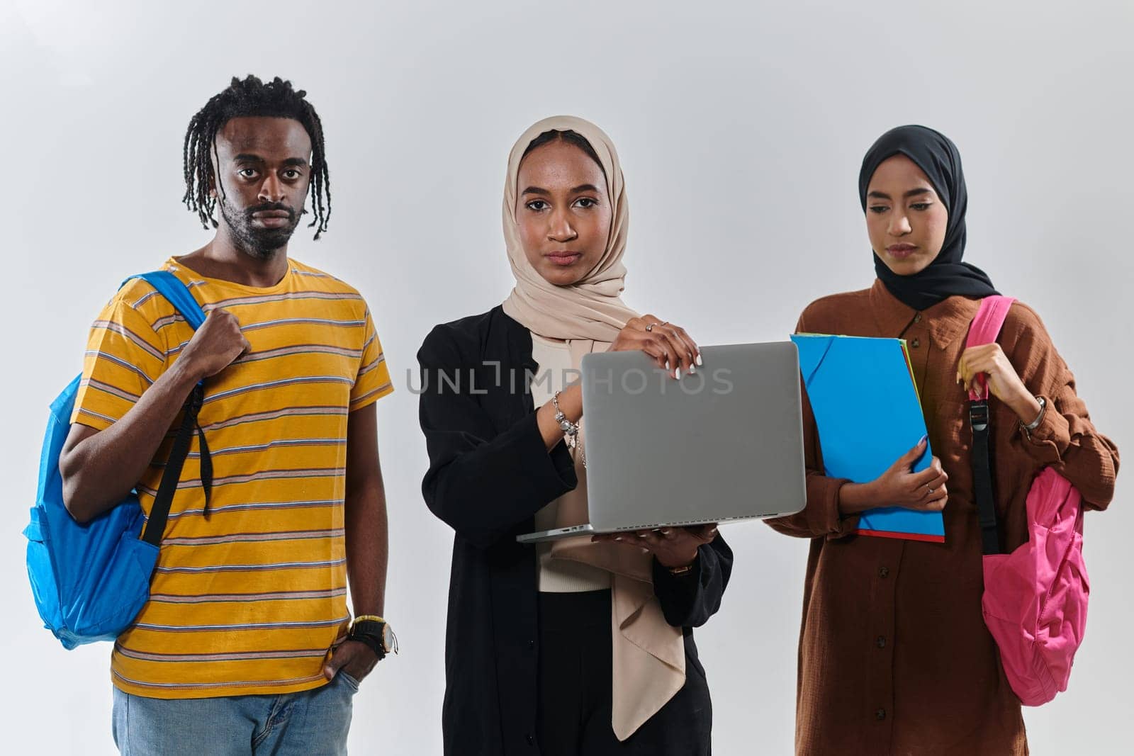 A group of students, including an African American student and two hijab-wearing women, stand united against a pristine white background, symbolizing a harmonious blend of cultures and backgrounds in the pursuit of knowledge and academic excellence.