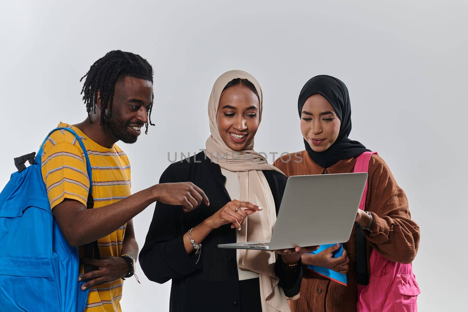 A group of students, including an African American student and two hijab-wearing women, stand united against a pristine white background, symbolizing a harmonious blend of cultures and backgrounds in the pursuit of knowledge and academic excellence by dotshock