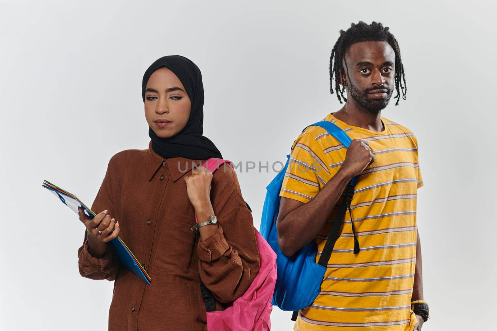 Against a clean white background, two students, an African American young man and a hijab-wearing woman, collaboratively use laptops in a display of technological empowerment and inclusive education, embodying the unity and diversity within the academic journey by dotshock