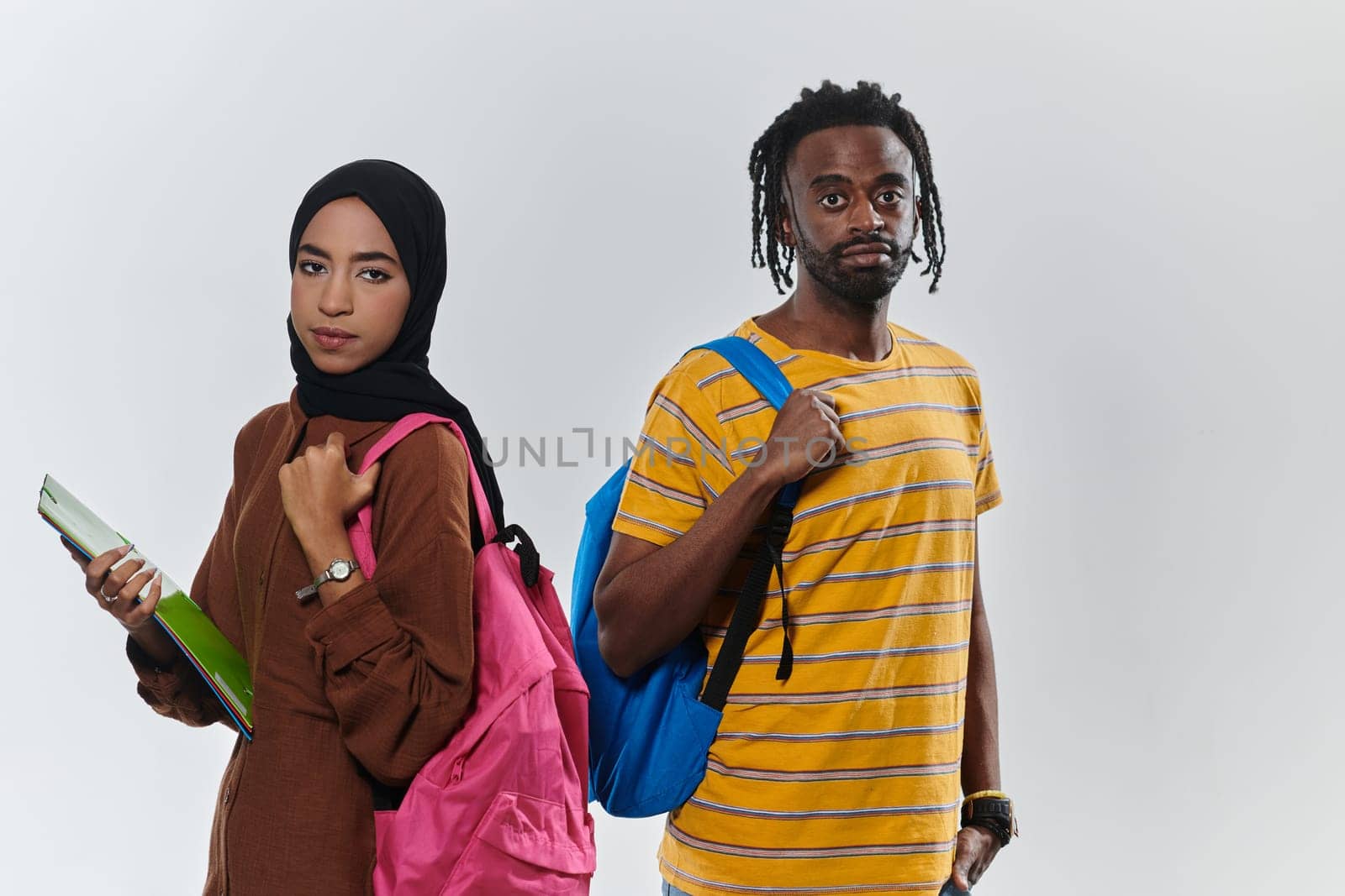 Against a clean white background, two students, an African American young man and a hijab-wearing woman, collaboratively use laptops in a display of technological empowerment and inclusive education, embodying the unity and diversity within the academic journey by dotshock