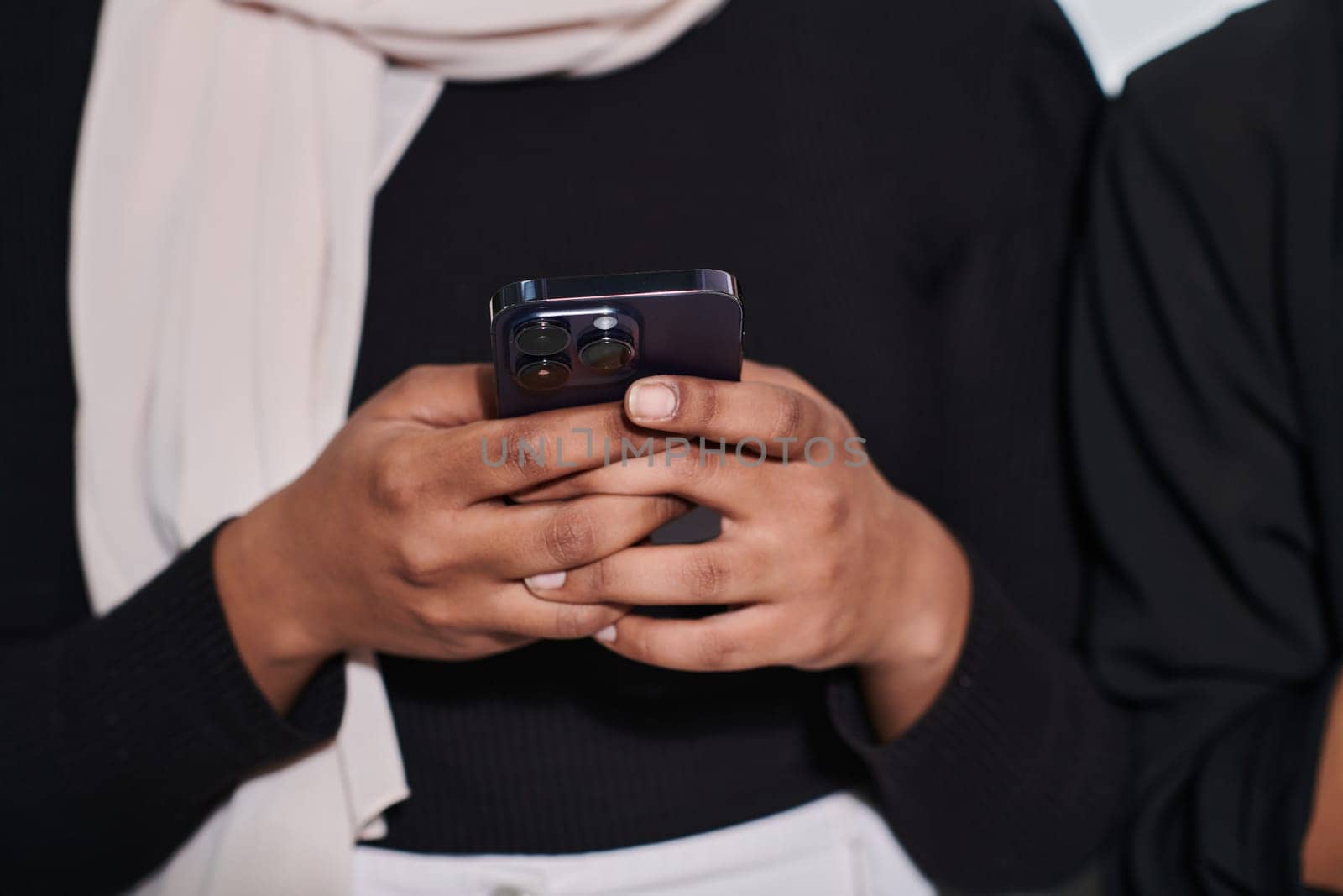 Captured in a close-up moment, a girl in hijab skillfully engages with her smartphone, reflecting a contemporary lifestyle where digital connectivity seamlessly intertwines with cultural expression, showcasing the empowerment and diversity embodied in modern technology usage by dotshock