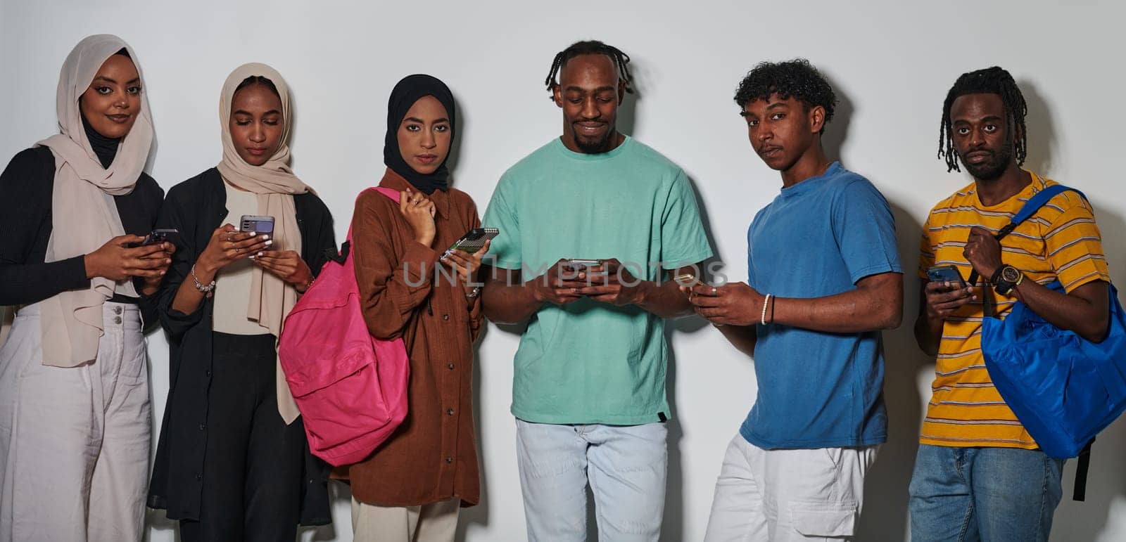 A diverse group of students, immersed in the digital age, stands united while engaging with their smartphones against a white backdrop, symbolizing the modern era of connectivity, communication, and collaborative learning.