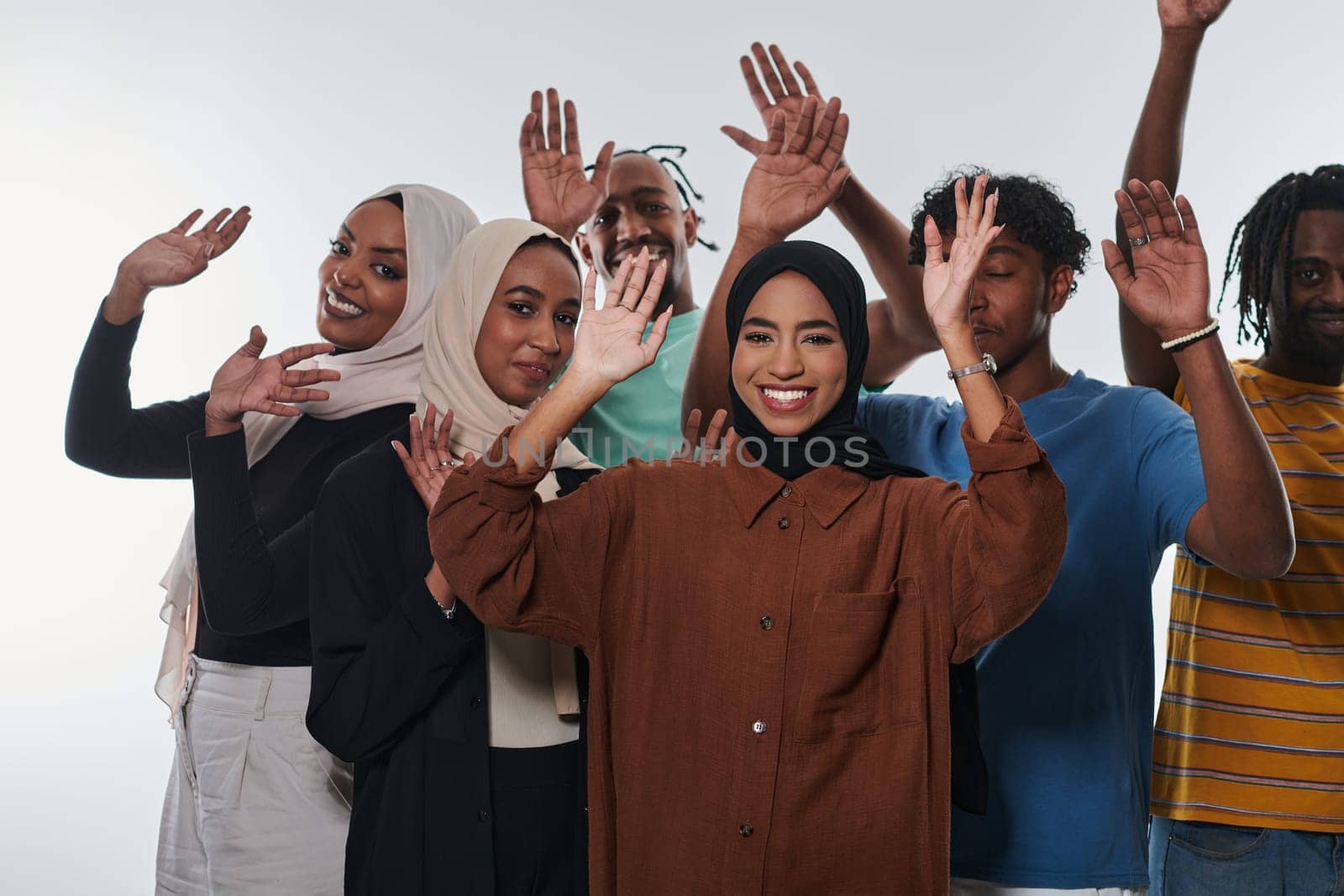 A jubilant and diverse group, including an African American man and hijab-wearing girls, exuberantly wave and celebrate, embodying the vibrancy of student life against a white backdrop, symbolizing unity, cultural diversity, and the joyous spirit of shared experiences by dotshock