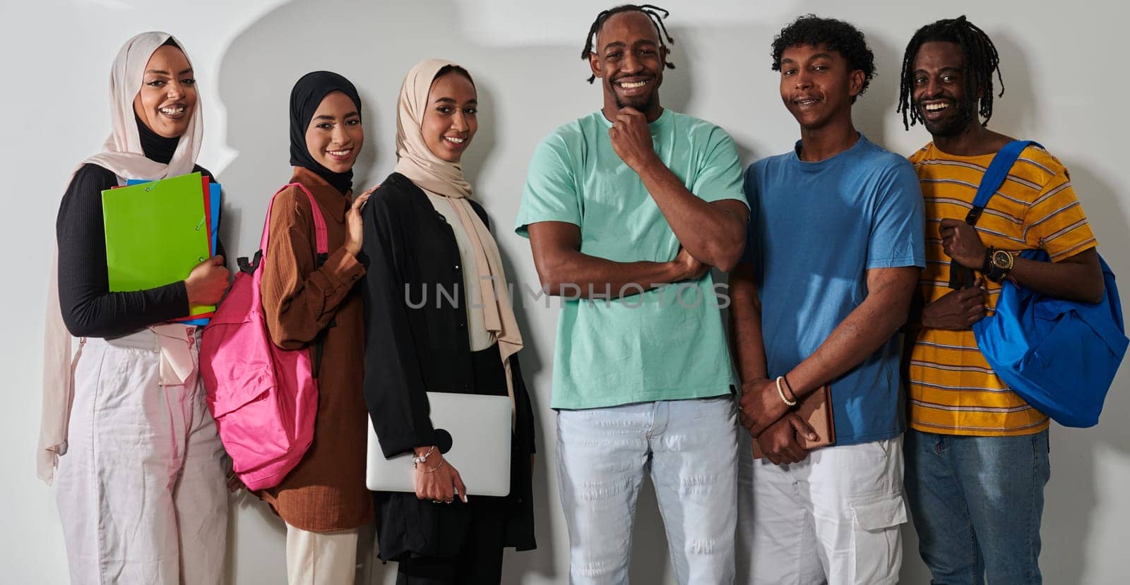 In a vibrant display of educational diversity, a group of students strikes a pose against a clean white background, holding backpacks, laptops, and tablets, symbolizing a blend of modern technology, unity, and cultural inclusivity in their academic journey.