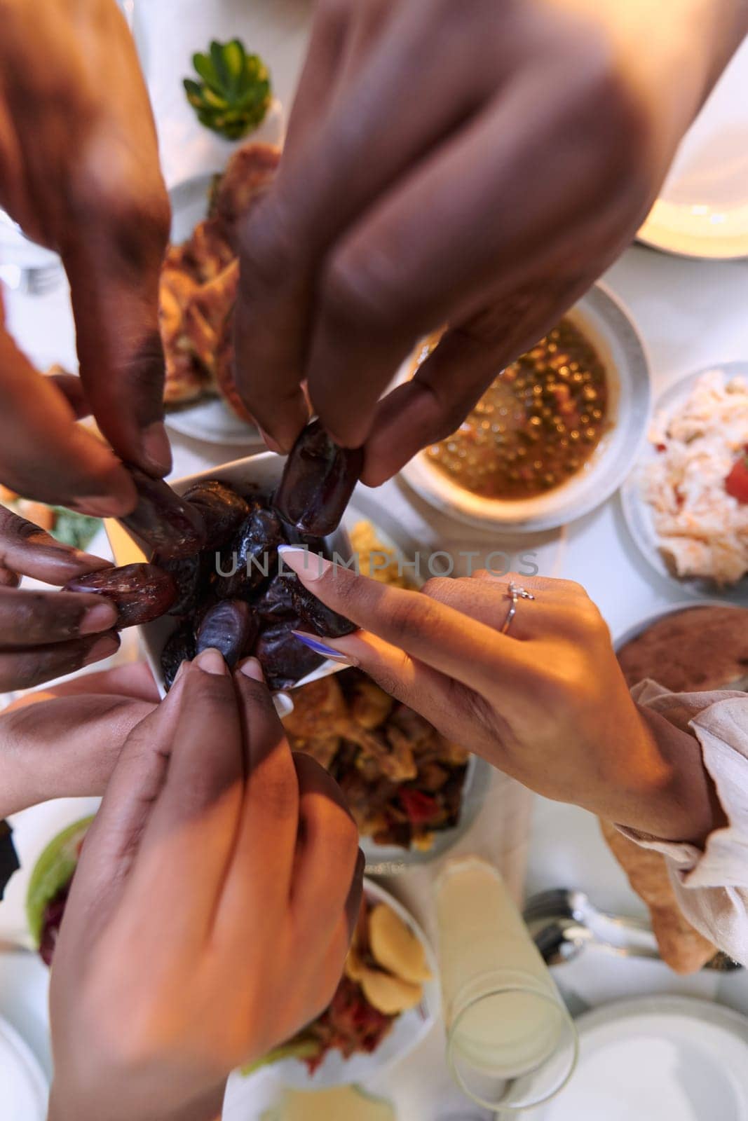 In a poignant close-up, the diverse hands of a Muslim family delicately grasp fresh dates, symbolizing the breaking of the fast during the holy month of Ramadan, capturing a moment of cultural unity, shared tradition, and the joyous anticipation of communal iftar by dotshock