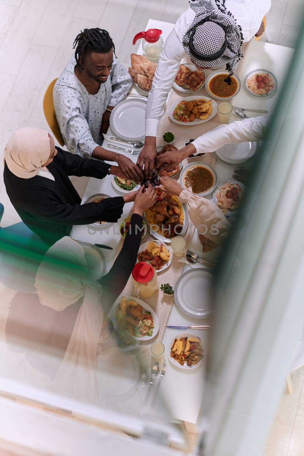 Top view of diverse hands of a Muslim family delicately grasp fresh dates, symbolizing the breaking of the fast during the holy month of Ramadan, capturing a moment of cultural unity, shared tradition, and the joyous anticipation of communal iftar by dotshock