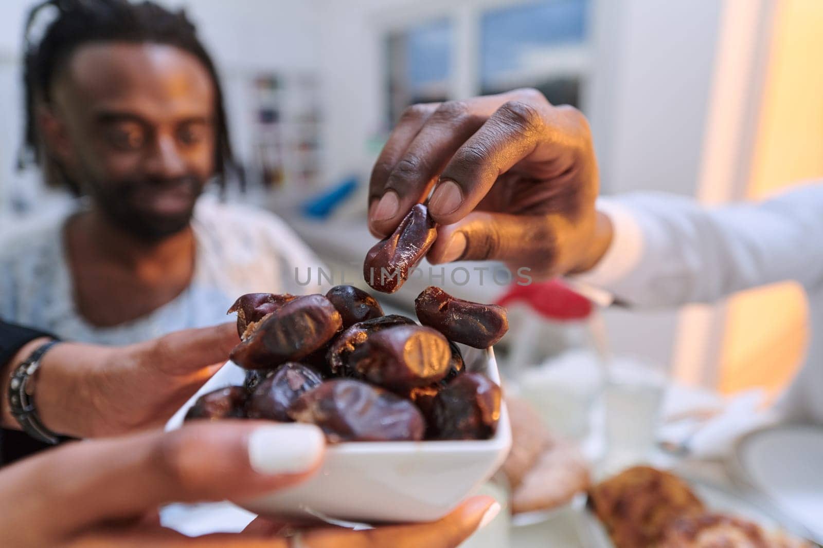 In a poignant close-up, the diverse hands of a Muslim family delicately grasp fresh dates, symbolizing the breaking of the fast during the holy month of Ramadan, capturing a moment of cultural unity, shared tradition, and the joyous anticipation of communal iftar by dotshock