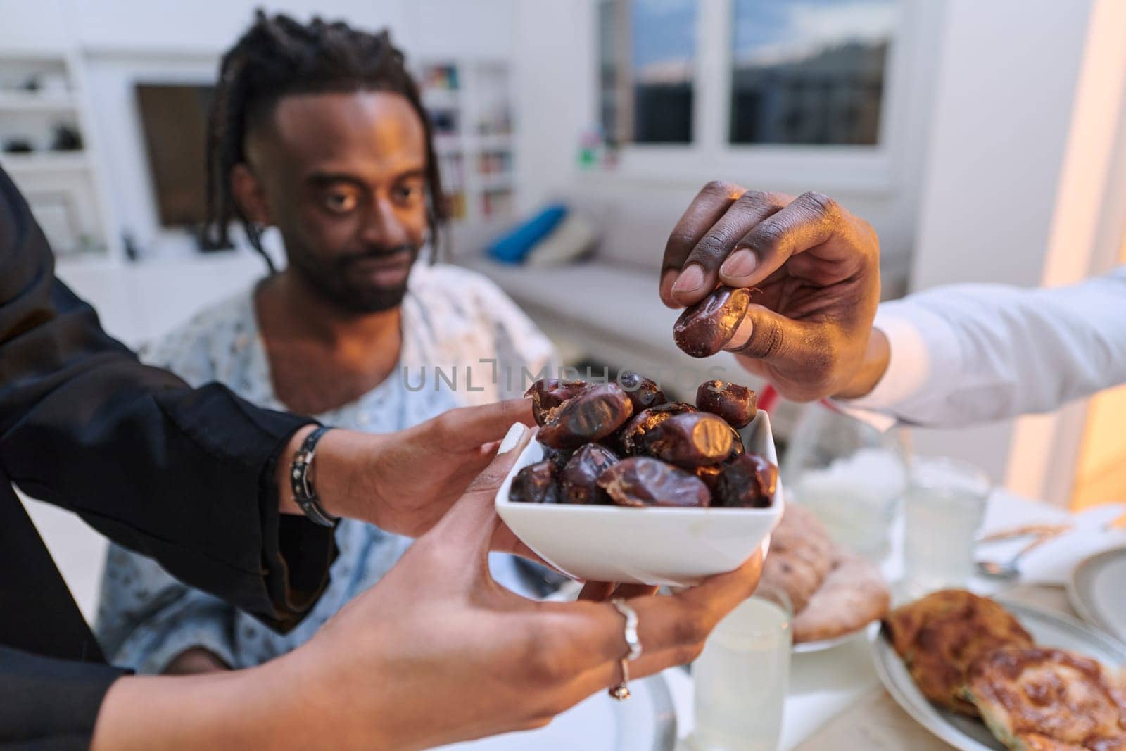 In a poignant close-up, the diverse hands of a Muslim family delicately grasp fresh dates, symbolizing the breaking of the fast during the holy month of Ramadan, capturing a moment of cultural unity, shared tradition, and the joyous anticipation of communal iftar by dotshock