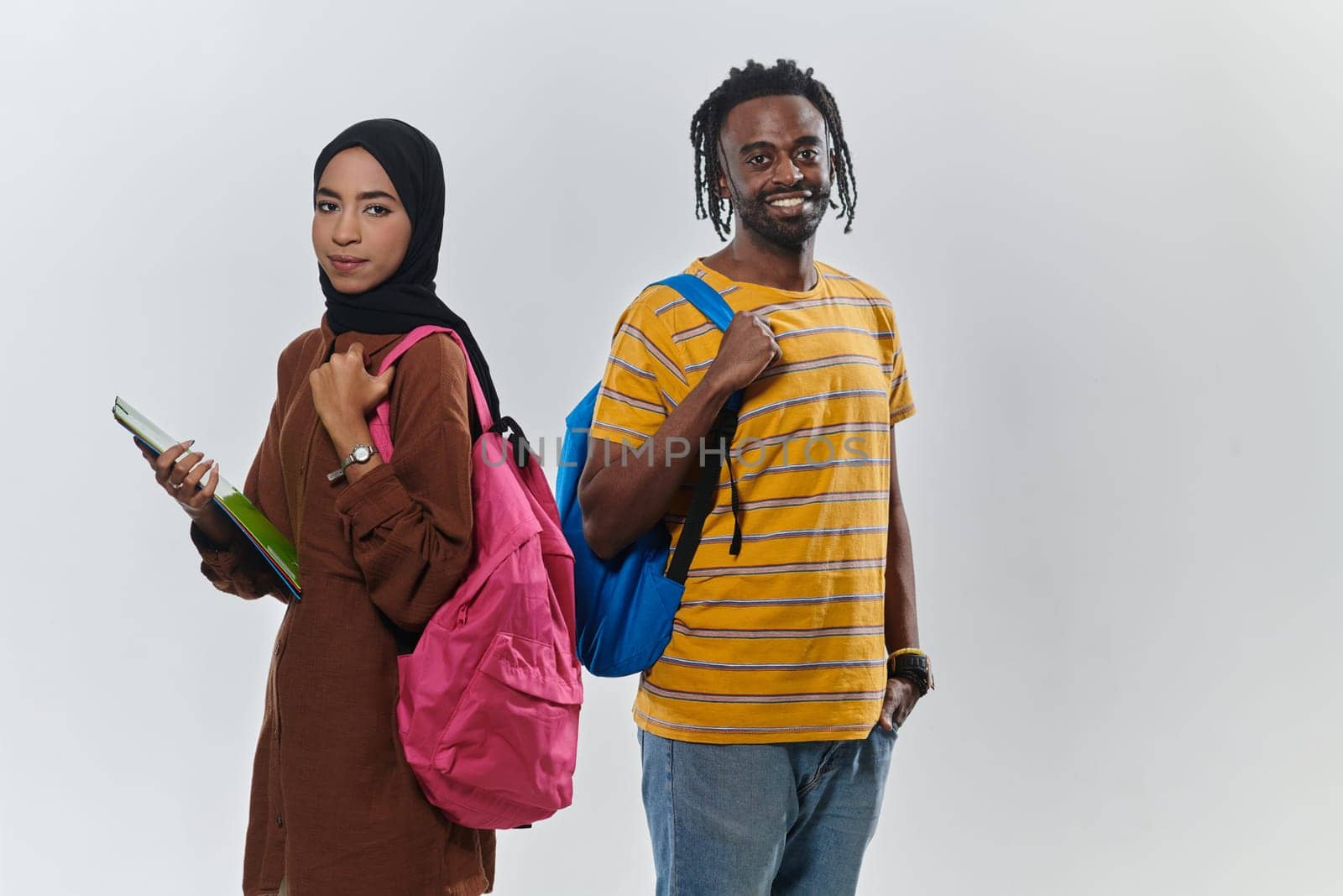 Against a clean white background, two students, an African American young man and a hijab-wearing woman, collaboratively use laptops in a display of technological empowerment and inclusive education, embodying the unity and diversity within the academic journey.