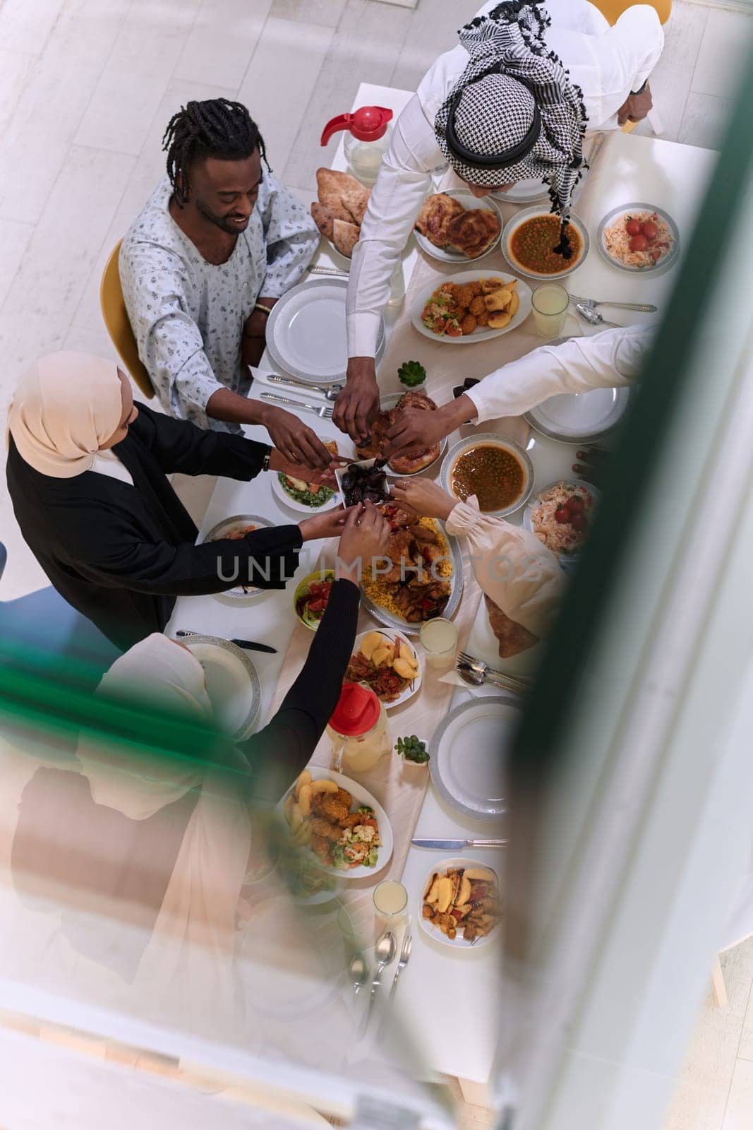 Top view of diverse hands of a Muslim family delicately grasp fresh dates, symbolizing the breaking of the fast during the holy month of Ramadan, capturing a moment of cultural unity, shared tradition, and the joyous anticipation of communal iftar.