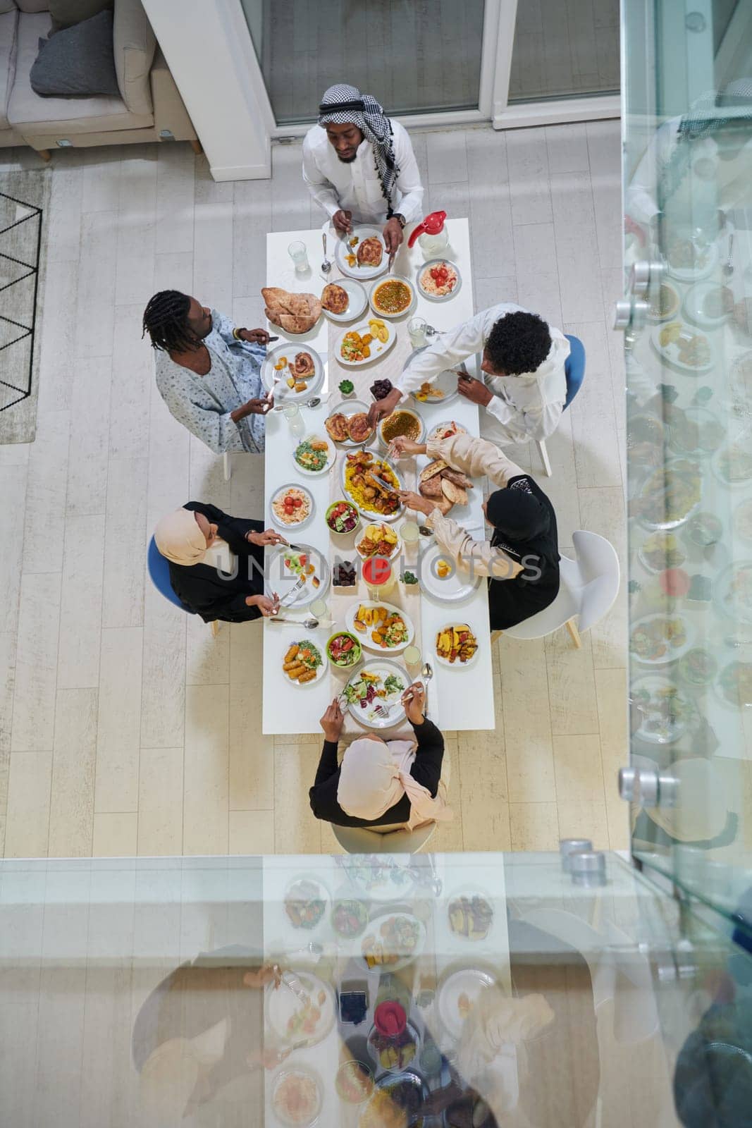Top view of traditional and diverse Muslim family comes together to share a delicious iftar meal during the sacred month of Ramadan, embodying the essence of familial joy, cultural richness, and spiritual unity in their shared celebration.