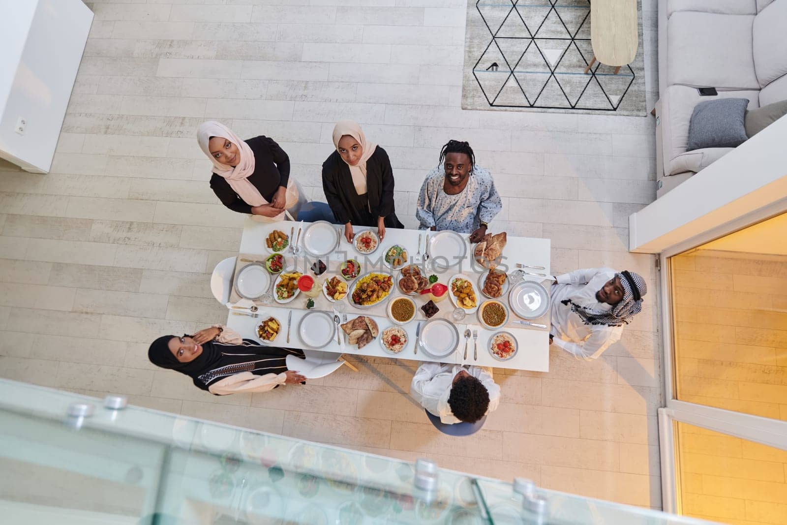 Top view of a Muslim family joyously comes together around a table, eagerly awaiting the communal iftar, engaging in the preparation of a shared meal, and uniting in anticipation of a collective prayer, embodying the spirit of togetherness, devotion, and cultural celebration.