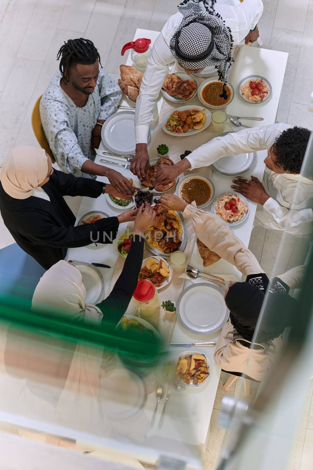 Top view of diverse hands of a Muslim family delicately grasp fresh dates, symbolizing the breaking of the fast during the holy month of Ramadan, capturing a moment of cultural unity, shared tradition, and the joyous anticipation of communal iftar by dotshock