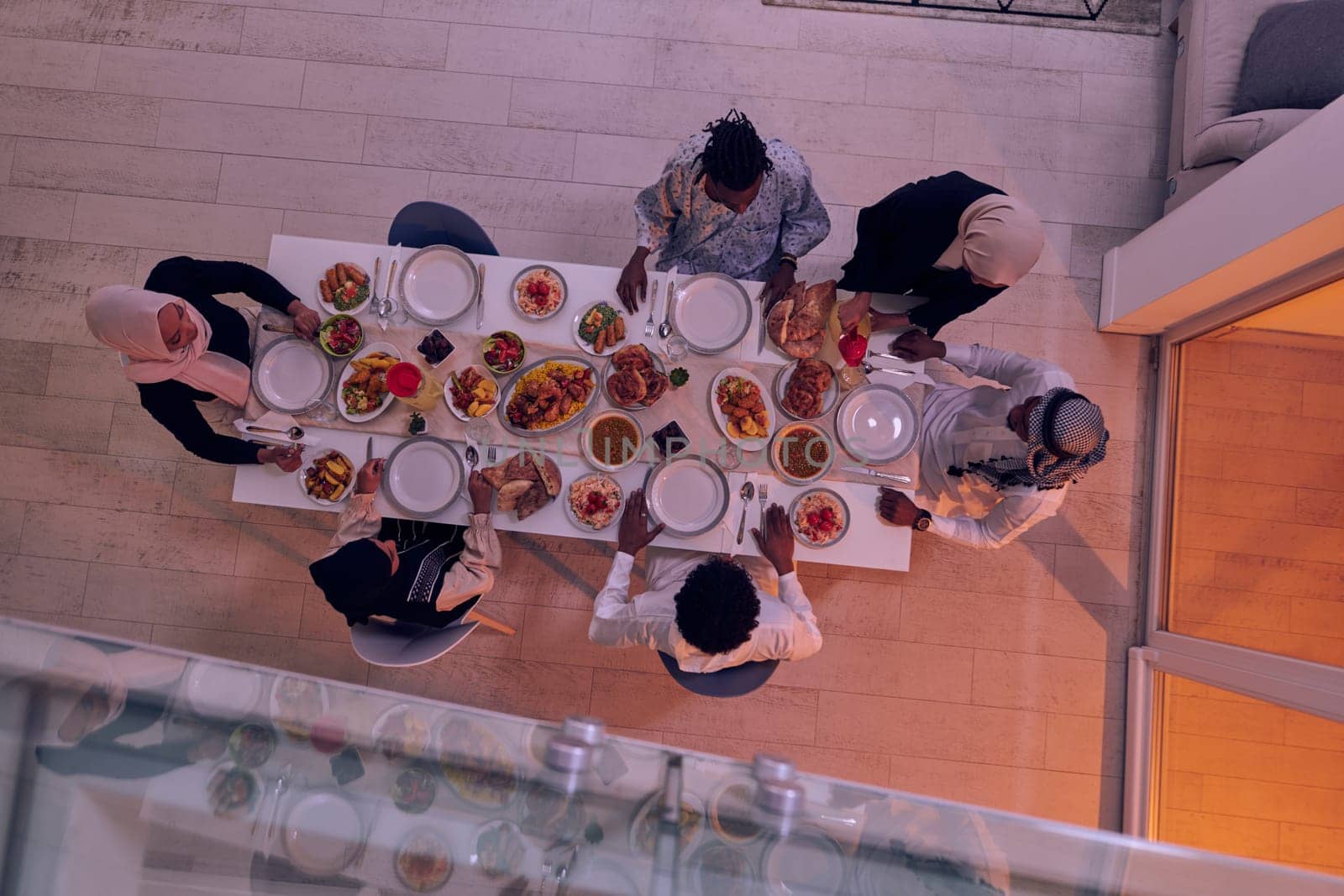 Top view of a Muslim family joyously comes together around a table, eagerly awaiting the communal iftar, engaging in the preparation of a shared meal, and uniting in anticipation of a collective prayer, embodying the spirit of togetherness, devotion, and cultural celebration.