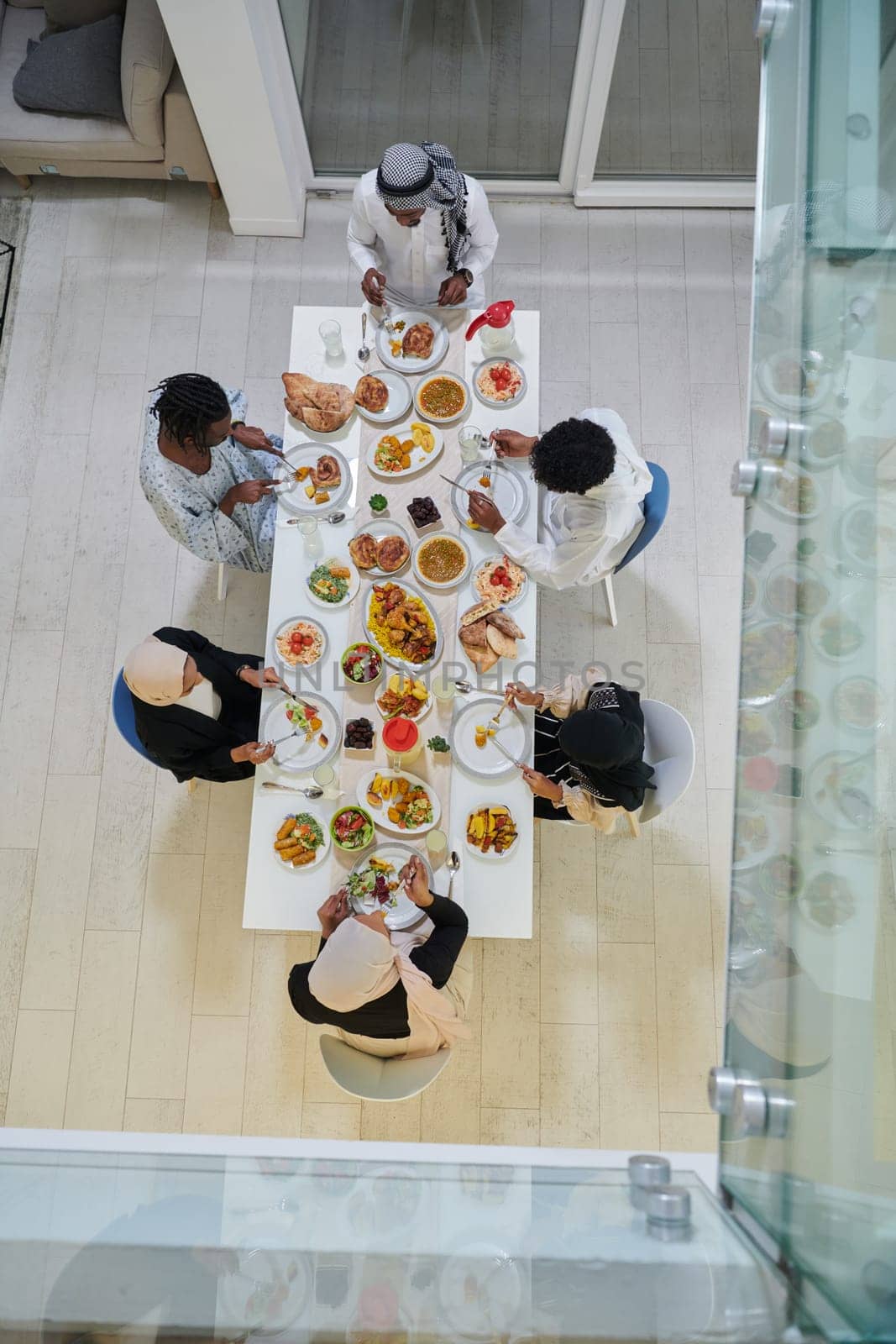 Top view of traditional and diverse Muslim family comes together to share a delicious iftar meal during the sacred month of Ramadan, embodying the essence of familial joy, cultural richness, and spiritual unity in their shared celebration by dotshock