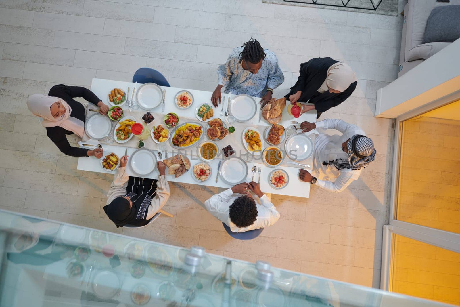 Top view of a Muslim family joyously comes together around a table, eagerly awaiting the communal iftar, engaging in the preparation of a shared meal, and uniting in anticipation of a collective prayer, embodying the spirit of togetherness, devotion, and cultural celebration.