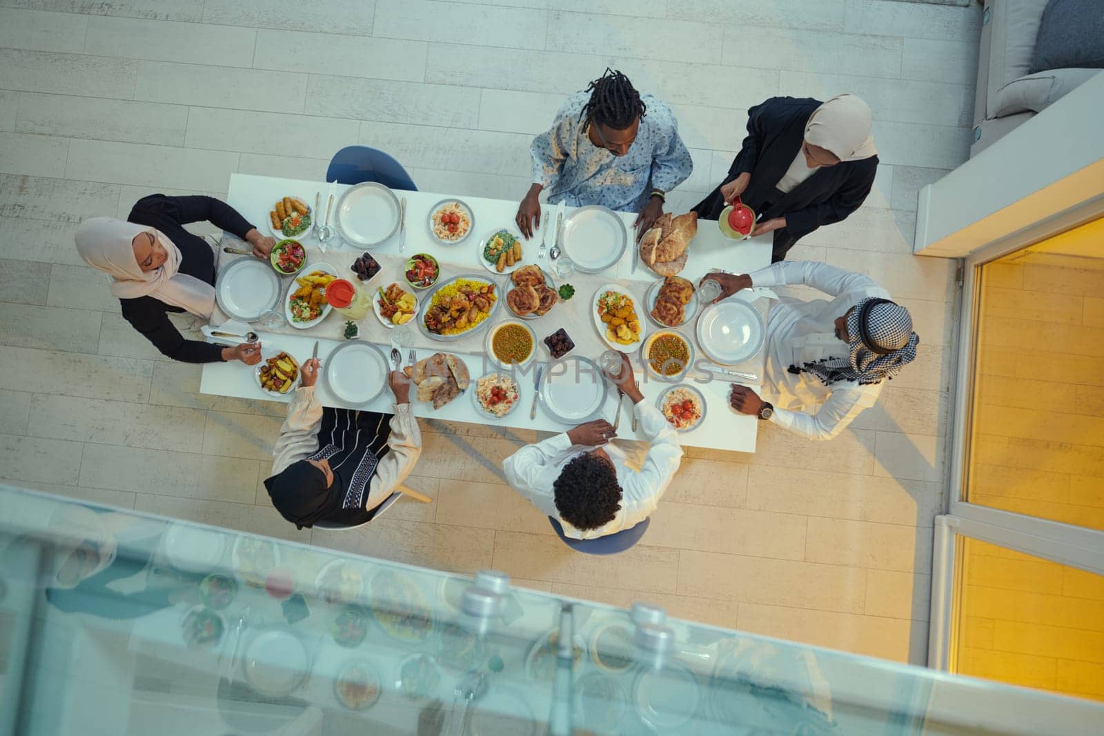 Top view of a Muslim family joyously comes together around a table, eagerly awaiting the communal iftar, engaging in the preparation of a shared meal, and uniting in anticipation of a collective prayer, embodying the spirit of togetherness, devotion, and cultural celebration.