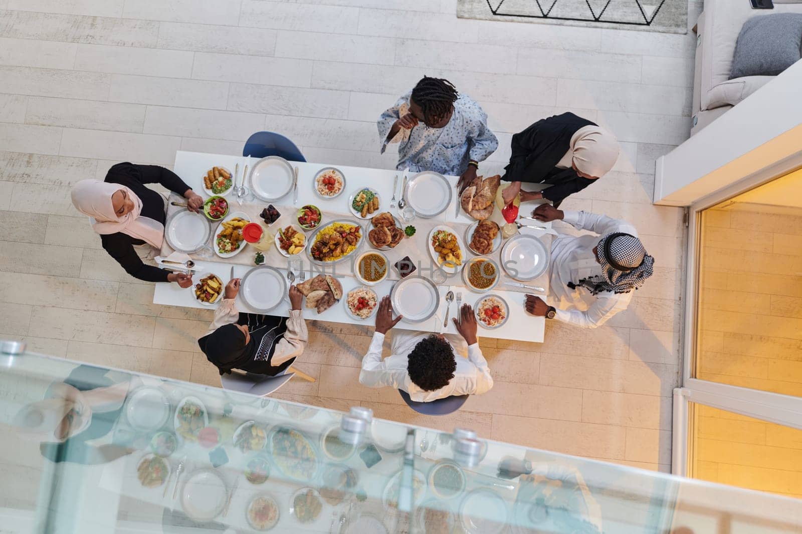 Top view of a Muslim family joyously comes together around a table, eagerly awaiting the communal iftar, engaging in the preparation of a shared meal, and uniting in anticipation of a collective prayer, embodying the spirit of togetherness, devotion, and cultural celebration.