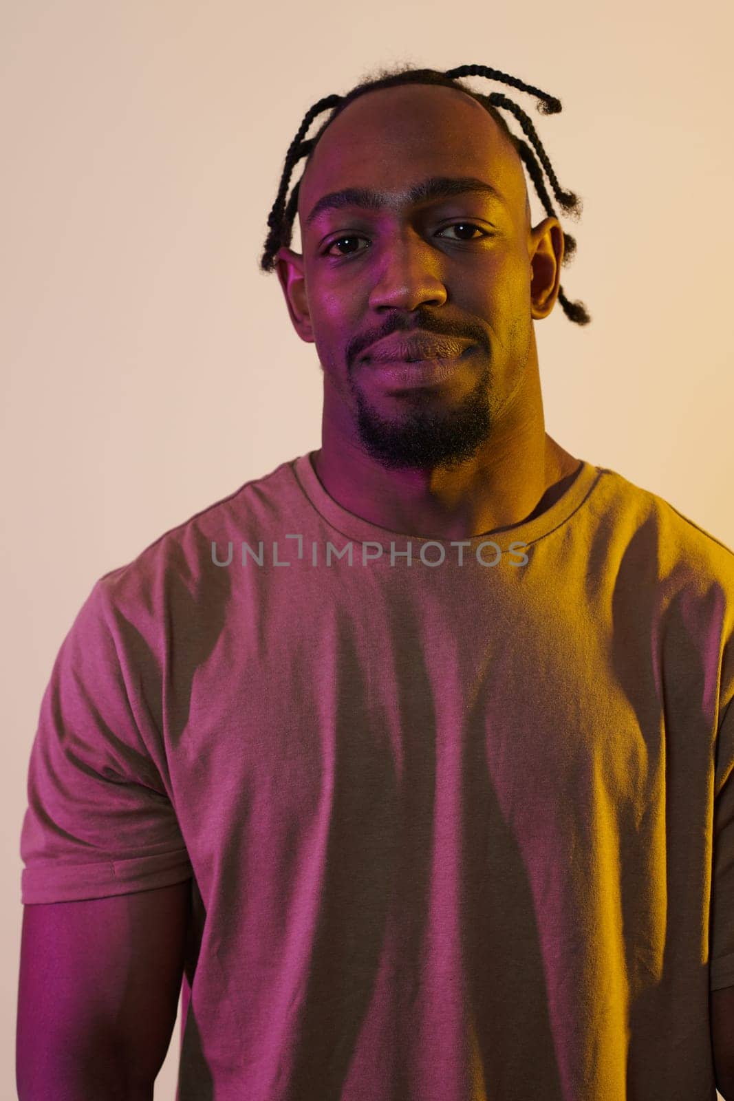 A charismatic and stylish African American man commands attention against a vibrant yellow gel background, showcasing his confident and contemporary fashion sense, radiating charm and sophistication in a striking portrait.