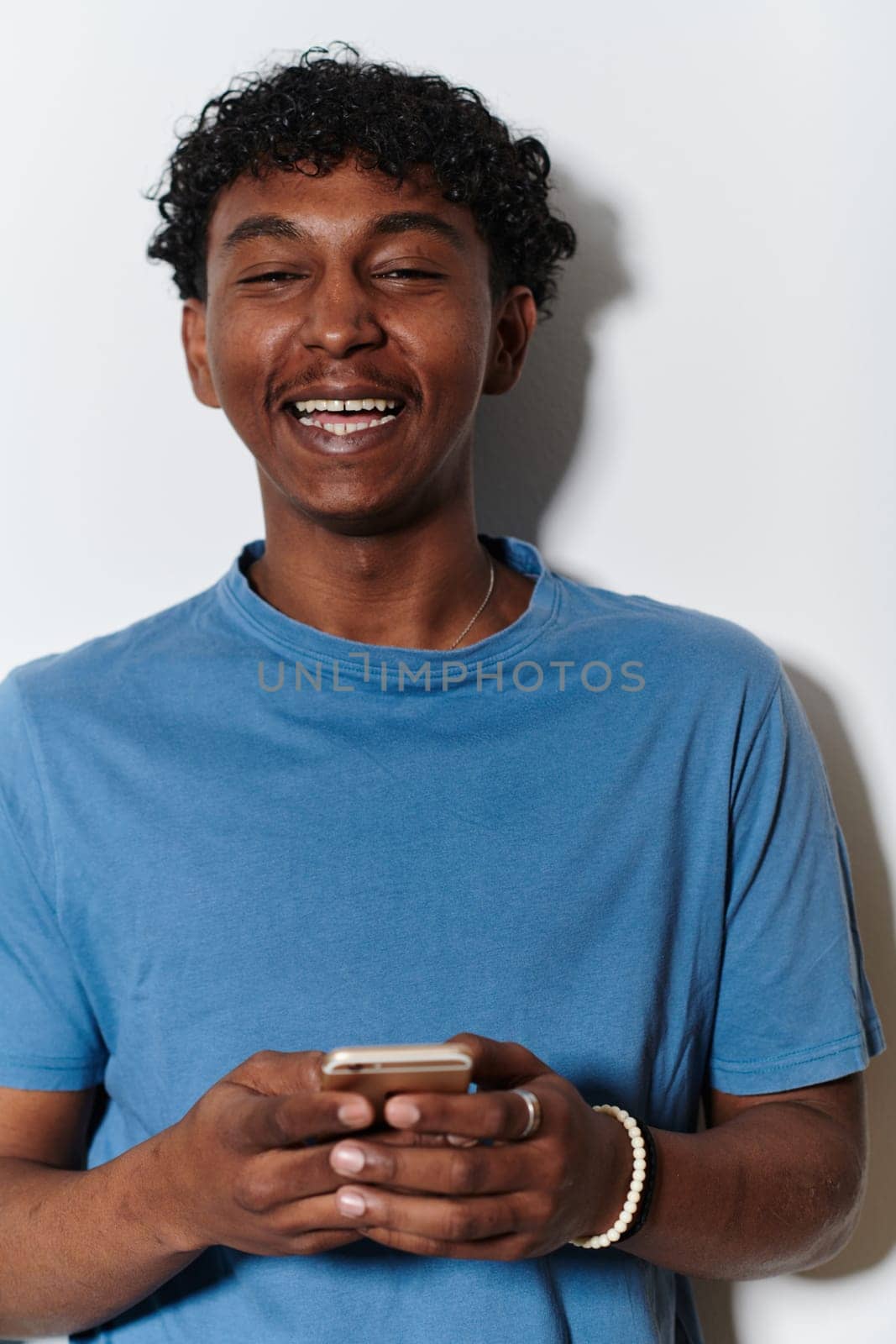 African American teenager engages with his smartphone against a pristine white background, encapsulating the essence of contemporary digital connectivity and youth culture.